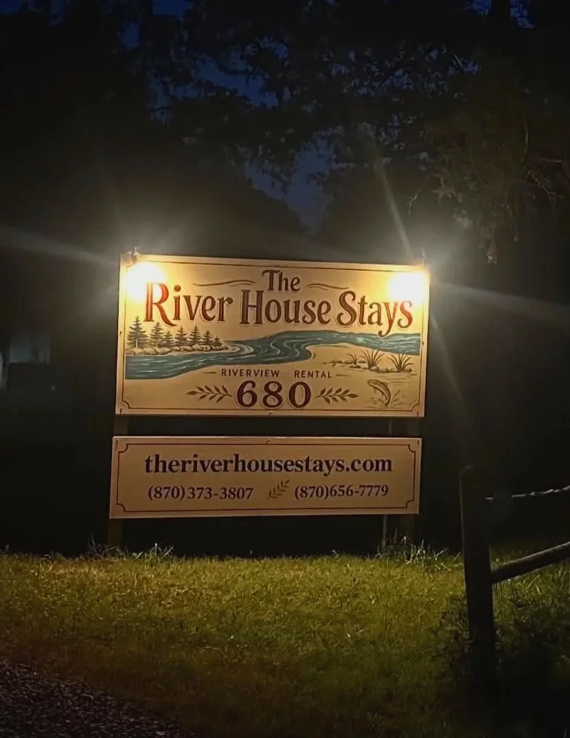 The River House Stays Sign Lit Up At Night