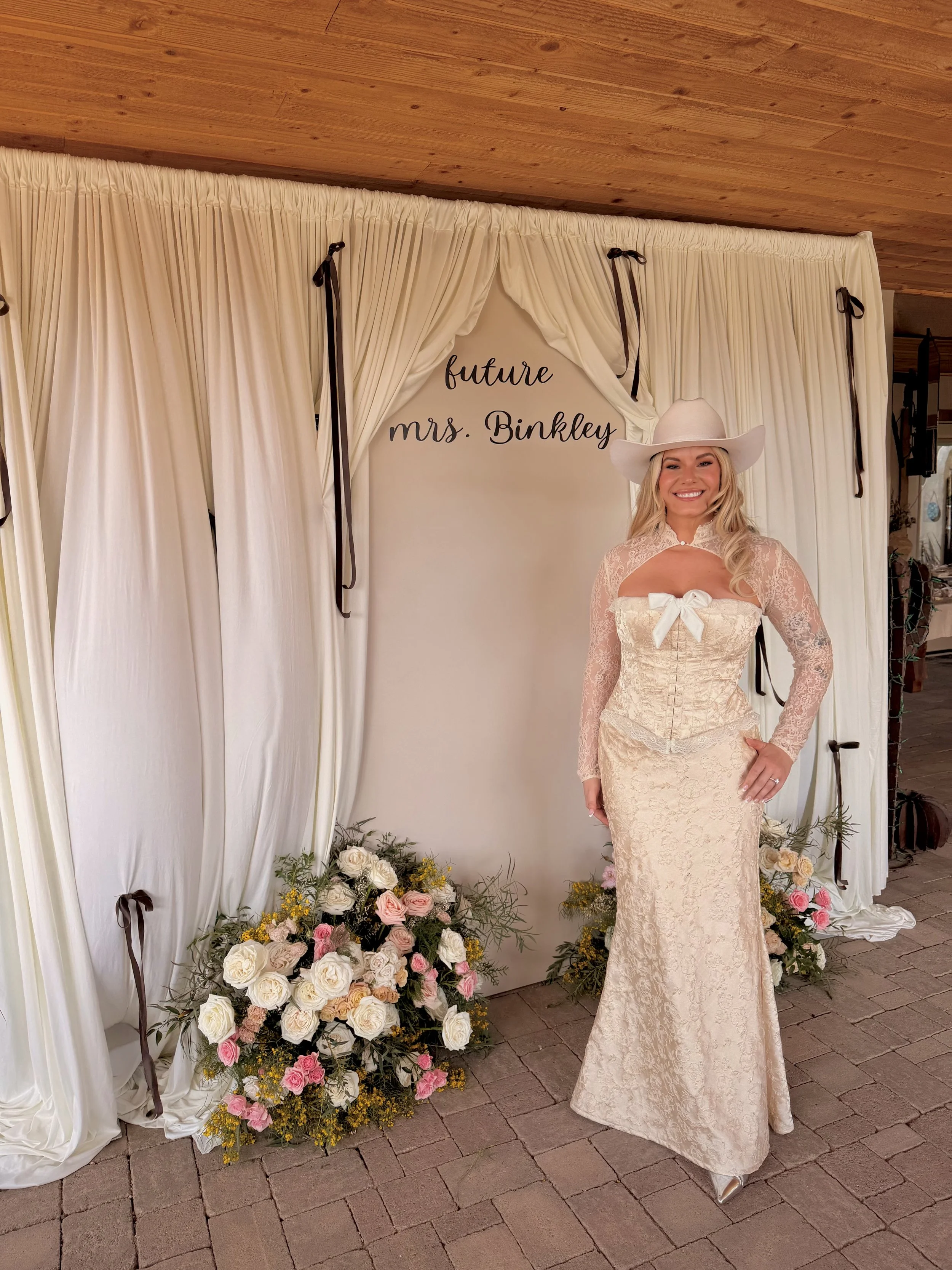 Elegant western-inspired bridal shower backdrop featuring custom ivory draping, romantic floral arrangements, and personalized "Future Mrs. Binkley" signage. This luxury bridal shower design blends timeless romance with modern western charm, creating