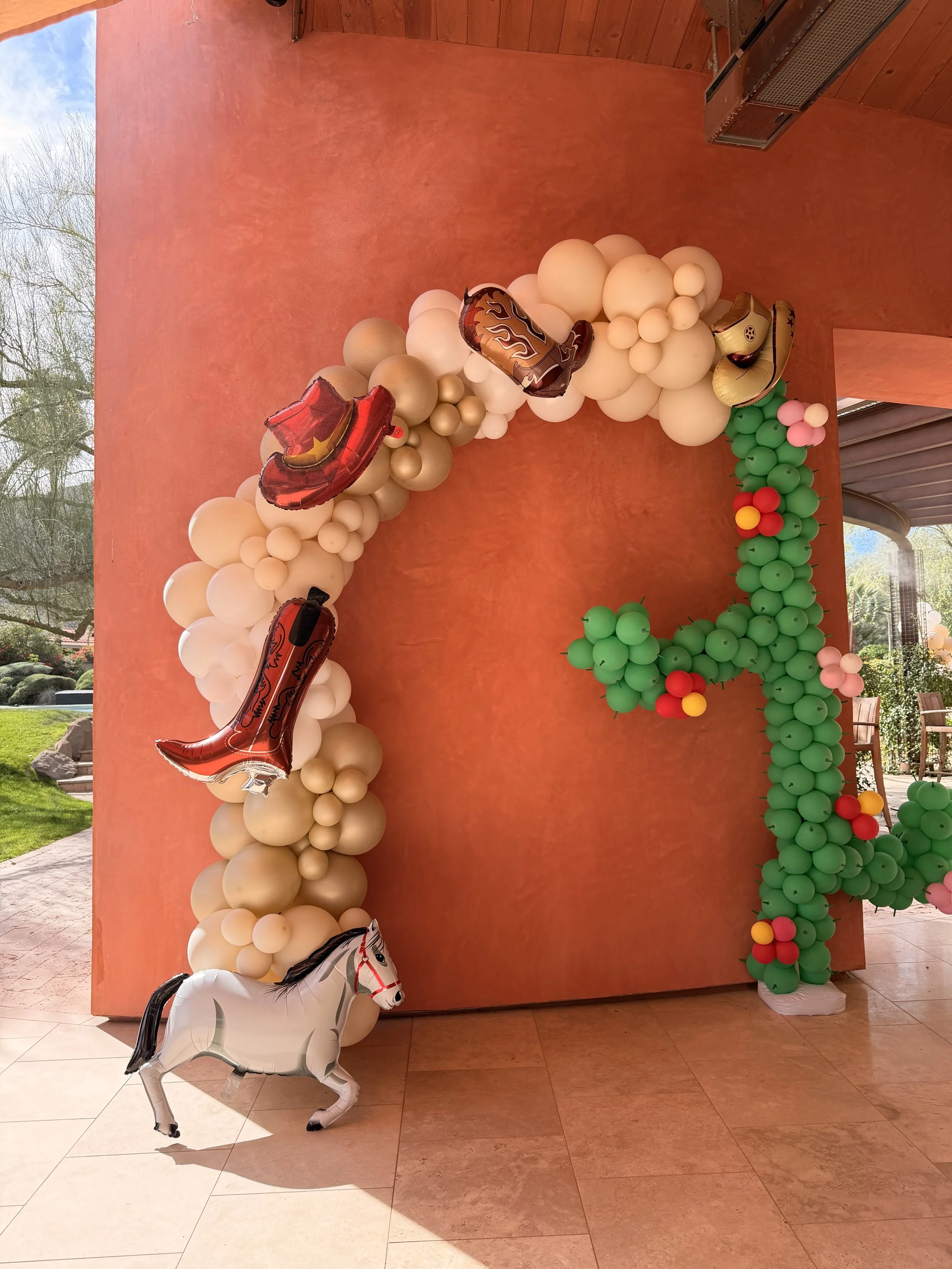Custom Wild West balloon installation featuring a cactus-shaped balloon sculpture, western-inspired balloon arch, cowboy boot and hat foil balloons, and horse-themed party décor. Designed for a western birthday party, rodeo celebration, cowboy-themed