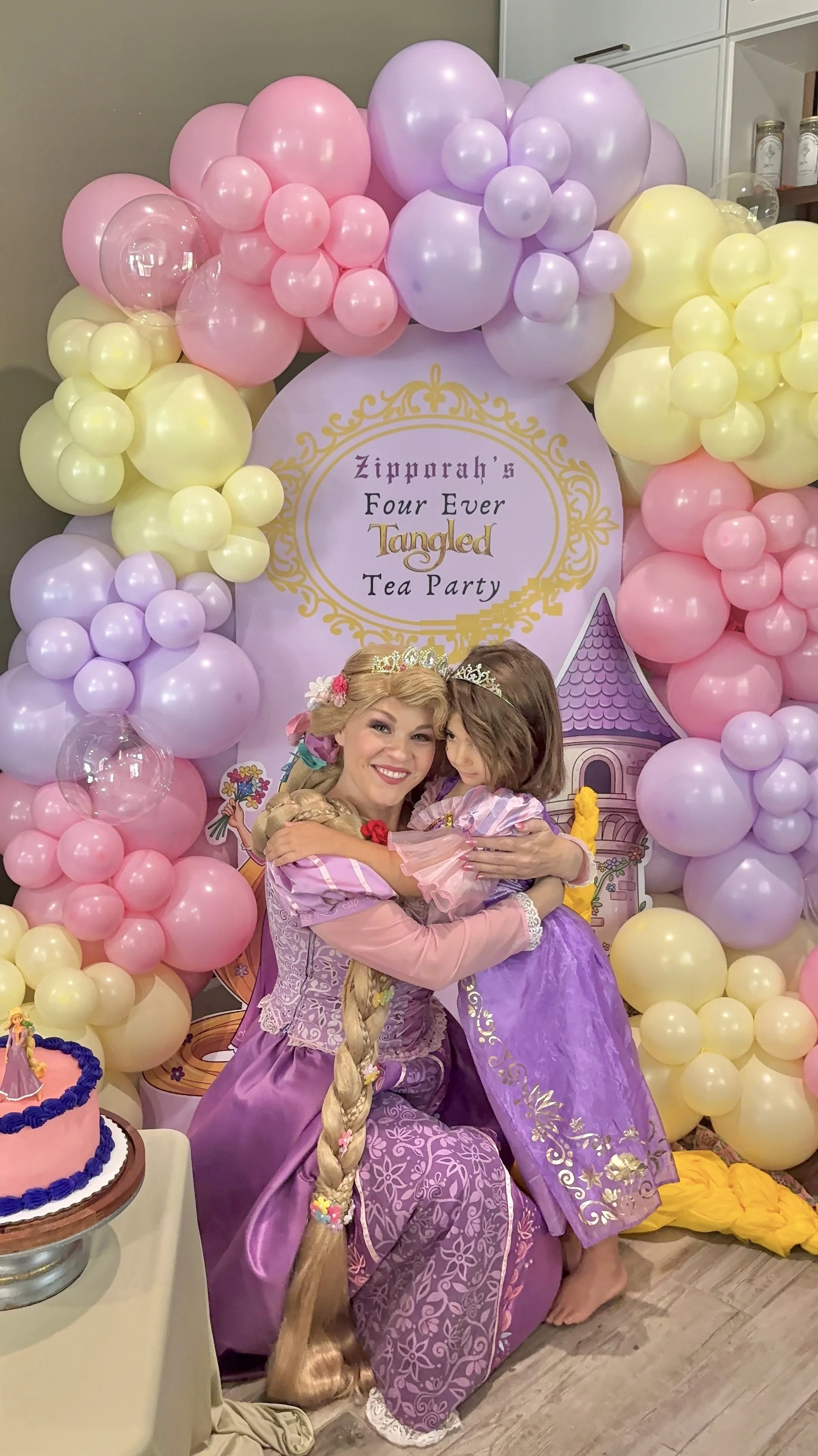 Magical Rapunzel princess birthday party featuring a custom "Zipporah's Four Ever Tangled Tea Party" backdrop, pastel pink, lavender, and buttercream balloon garlands, princess character entertainment, and fairytale-inspired décor. This enchanting bi
