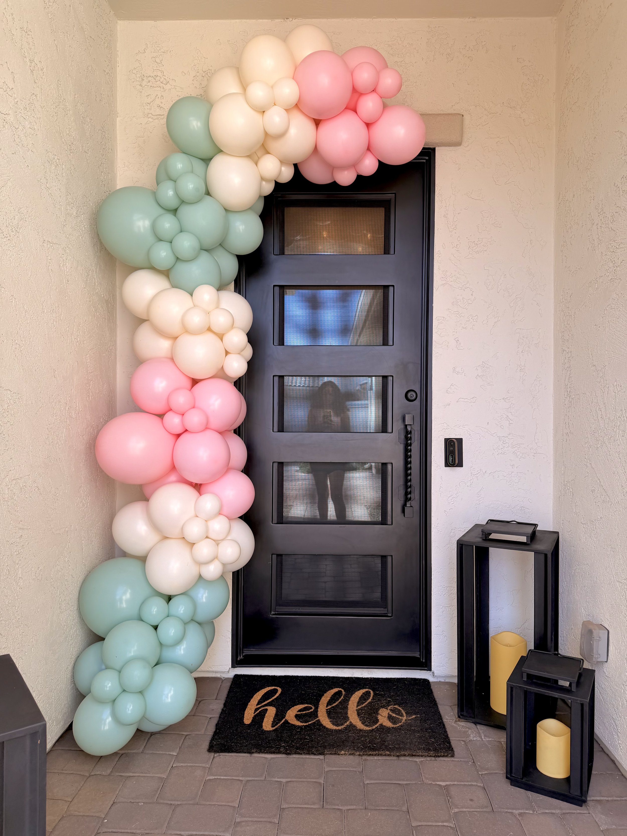 Custom front door balloon garland featuring blush pink, mint green, ivory, and white balloons designed for a baby shower welcome entrance. This organic balloon installation creates a beautiful first impression for guests and is perfect for baby showe