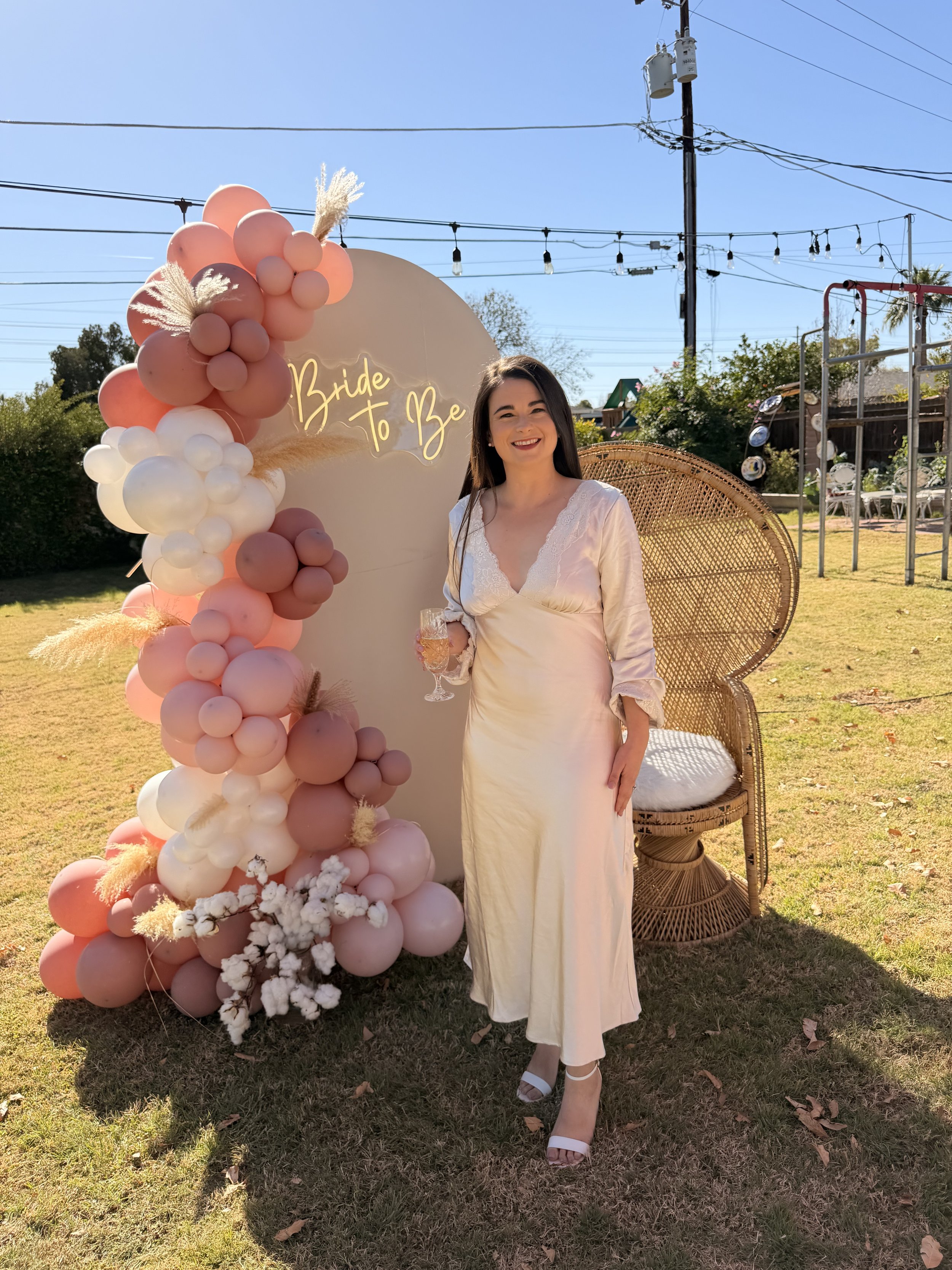 Elegant bridal shower backdrop featuring a custom "Bride to Be" sign, blush pink and white organic balloon garland, pampas grass accents, and boho-inspired event styling. This luxury bridal shower installation created the perfect photo opportunity fo