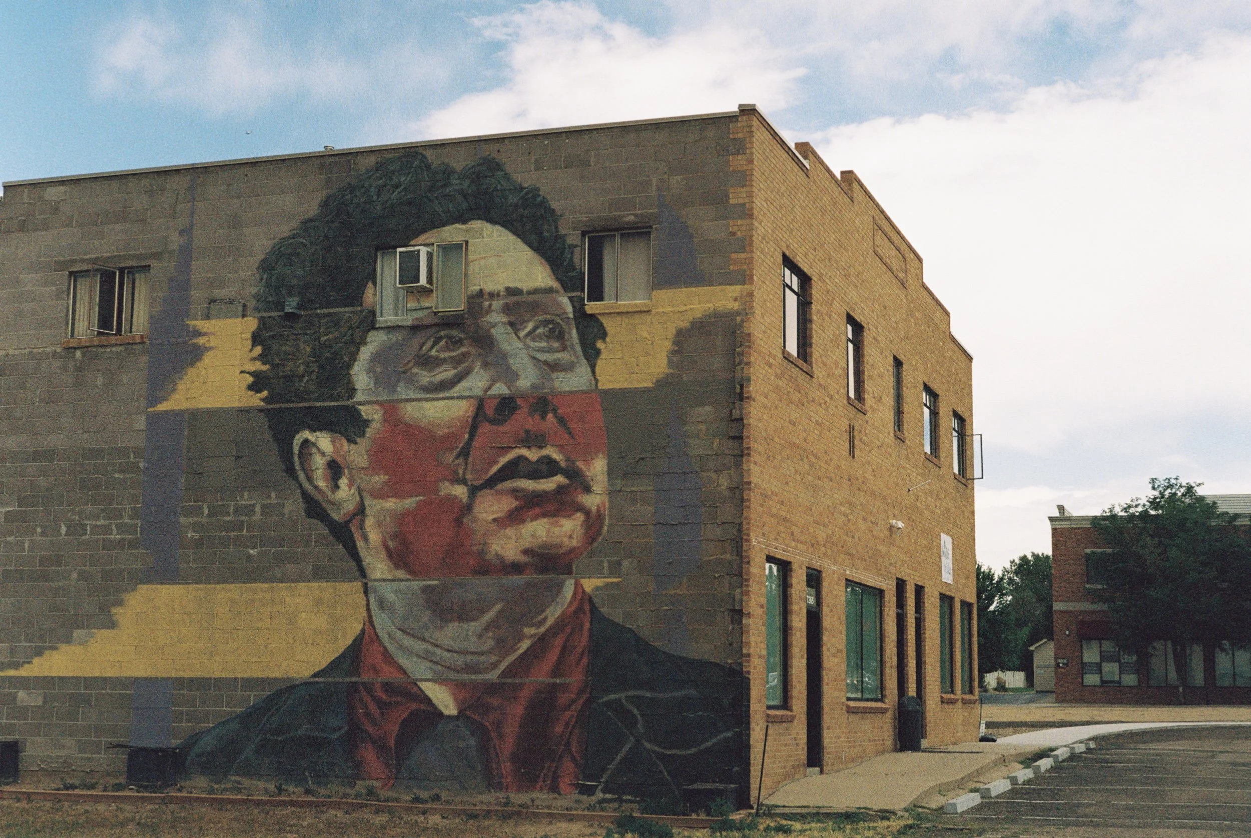 A mural of a woman's face on the side of a brick building against a cloudy sky.