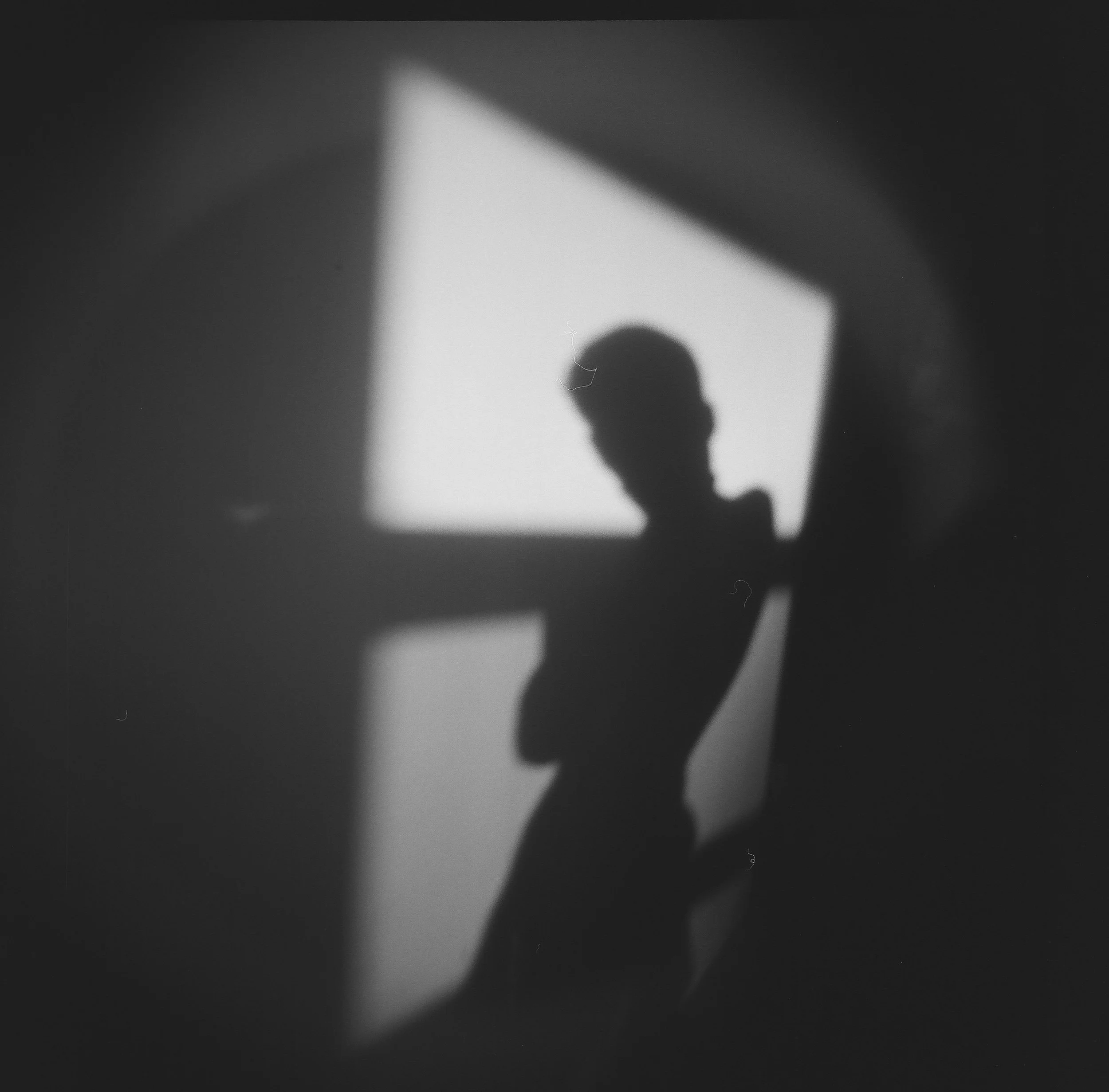 Black and white photo of a person’s silhouette with a spotlight shining on the wall.