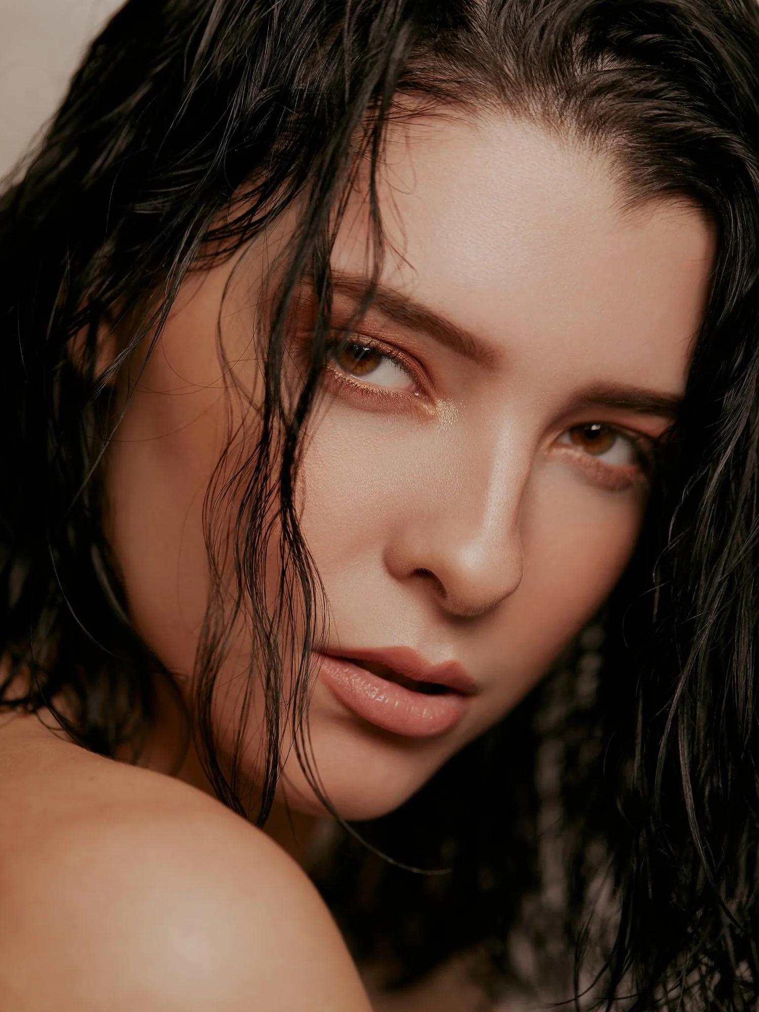 Close-up of a woman's face showing her brown eyes, wet black hair, and lips.