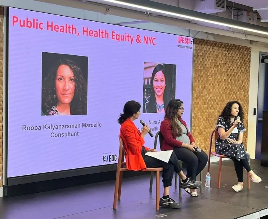 Three women sitting on chairs, participating in a panel discussion on public health, health equity, and NYC, with a large screen behind them displaying their names and titles. The screen shows headshots of Roopa Kalyanaraman Marcello and Nura Ahmed, along with the event title and logos.
