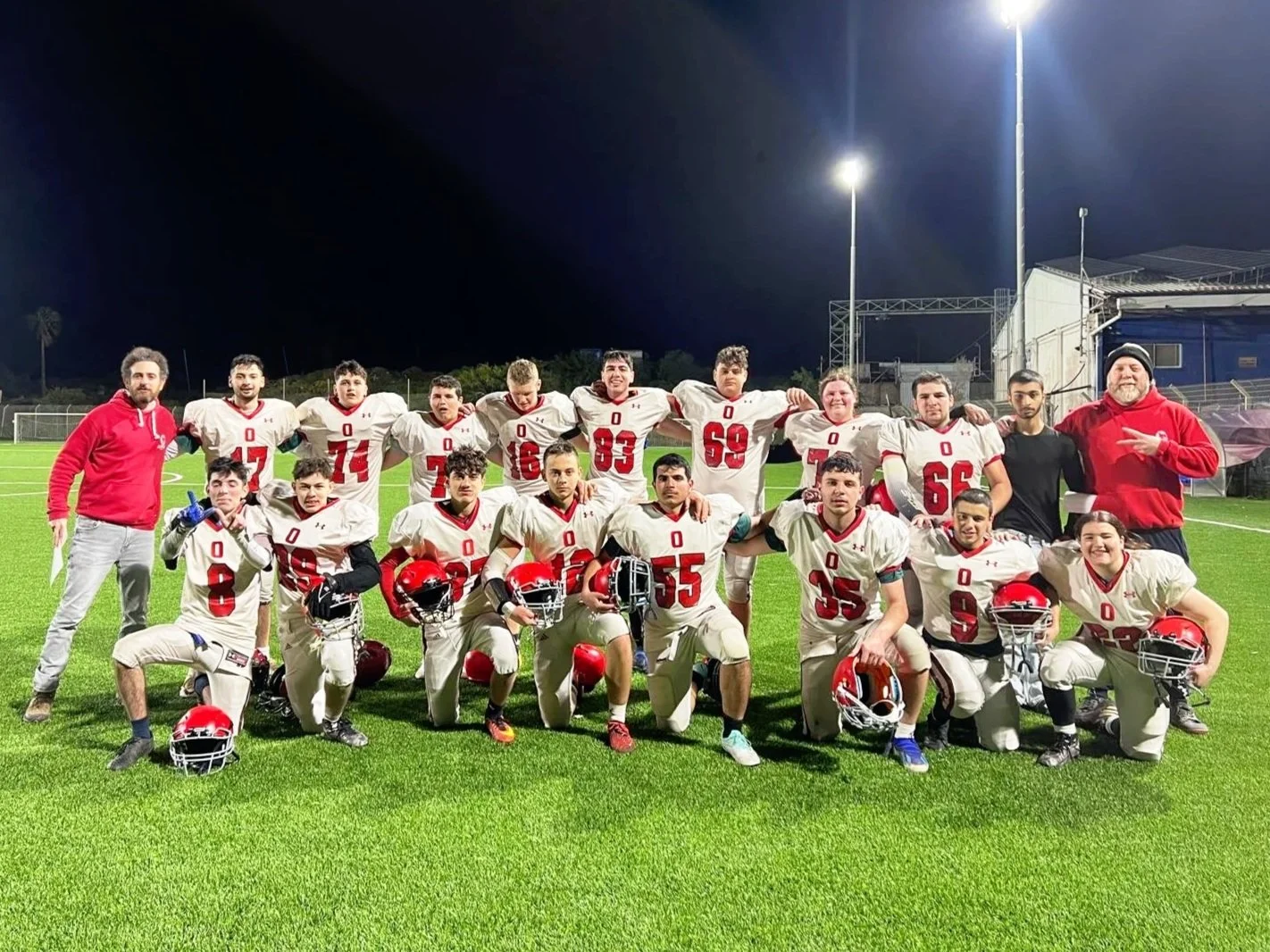 Kadoorie football team posing on a field at night.