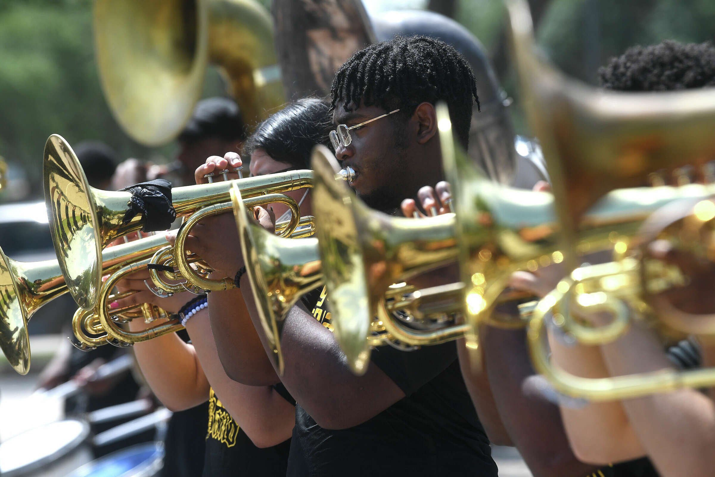 Group of musicians playing brass instruments outdoors in a parade or event.