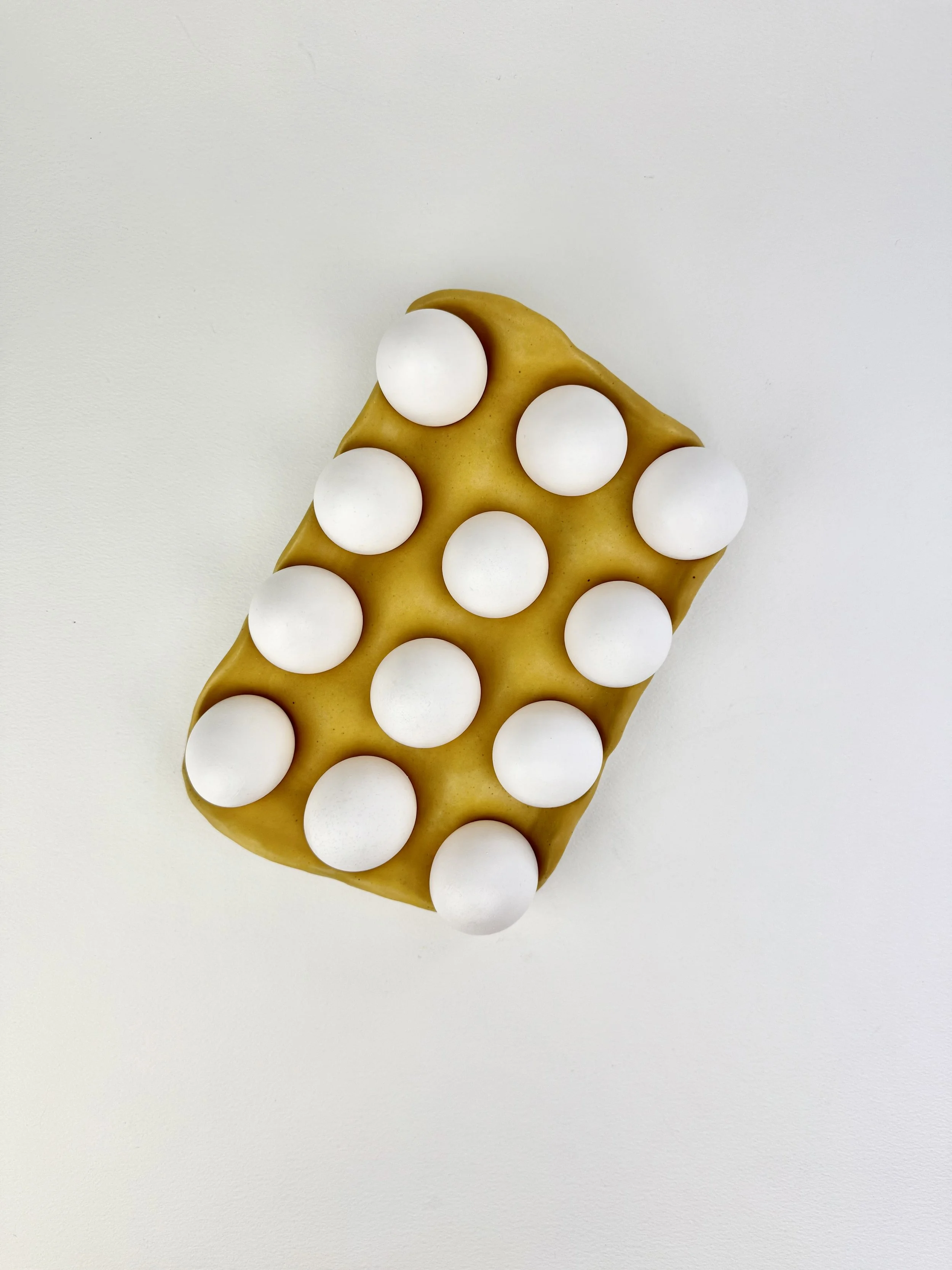 A yellow object with rounded edges and multiple white spheres on its surface.