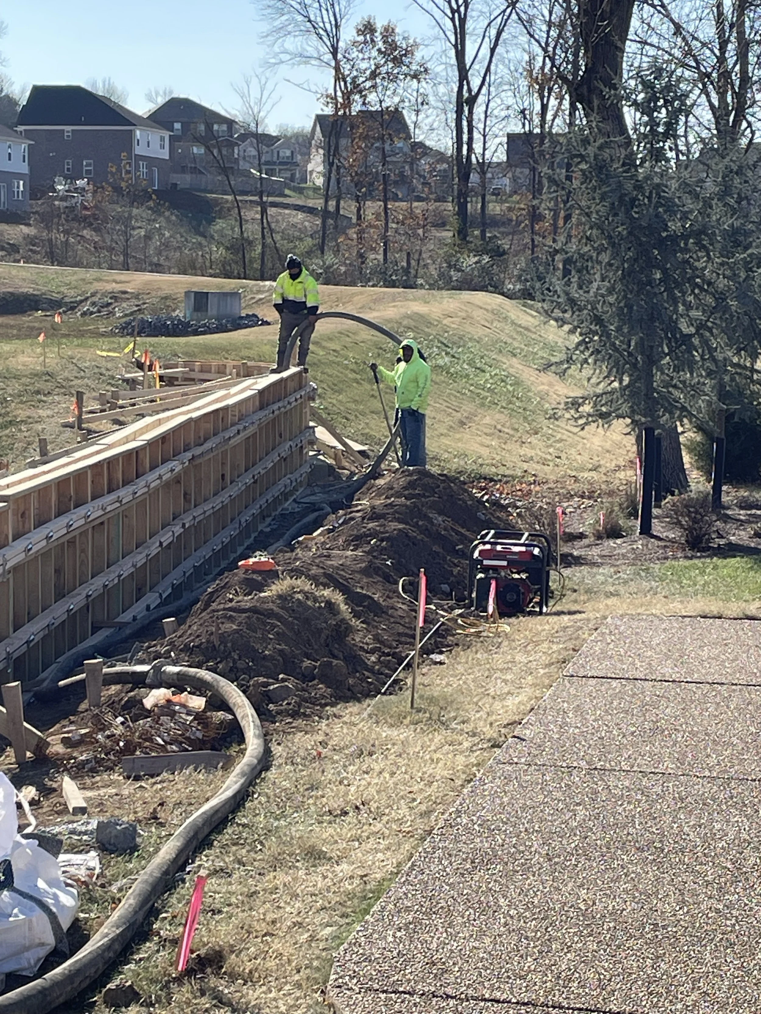 Construction workers installing a retaining wall on a residential property during daytime