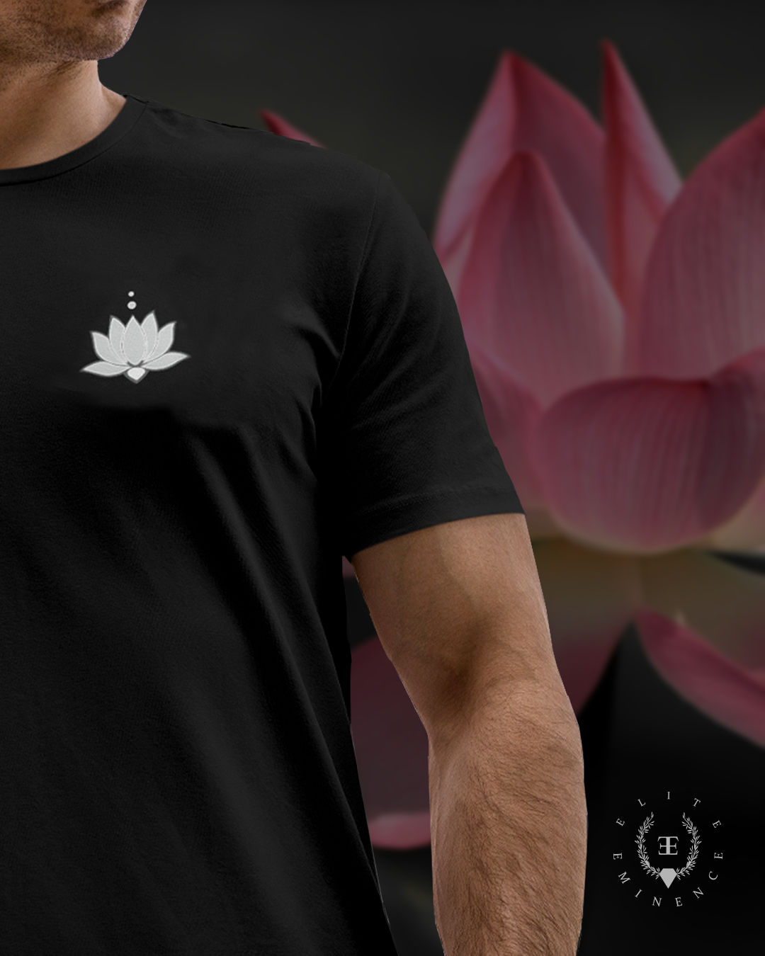 Close-up of a person wearing a black T-shirt with a white lotus flower logo on the chest, standing in front of a blurred background of pink lotus flowers.