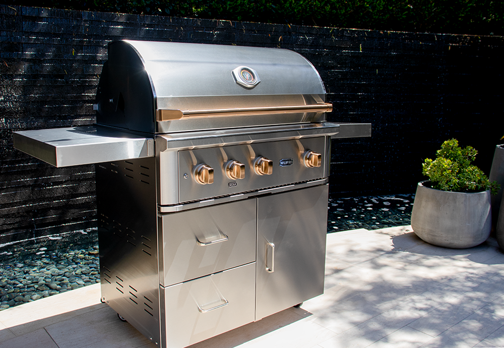 A stainless steel outdoor gas grill with side shelves on a patio.