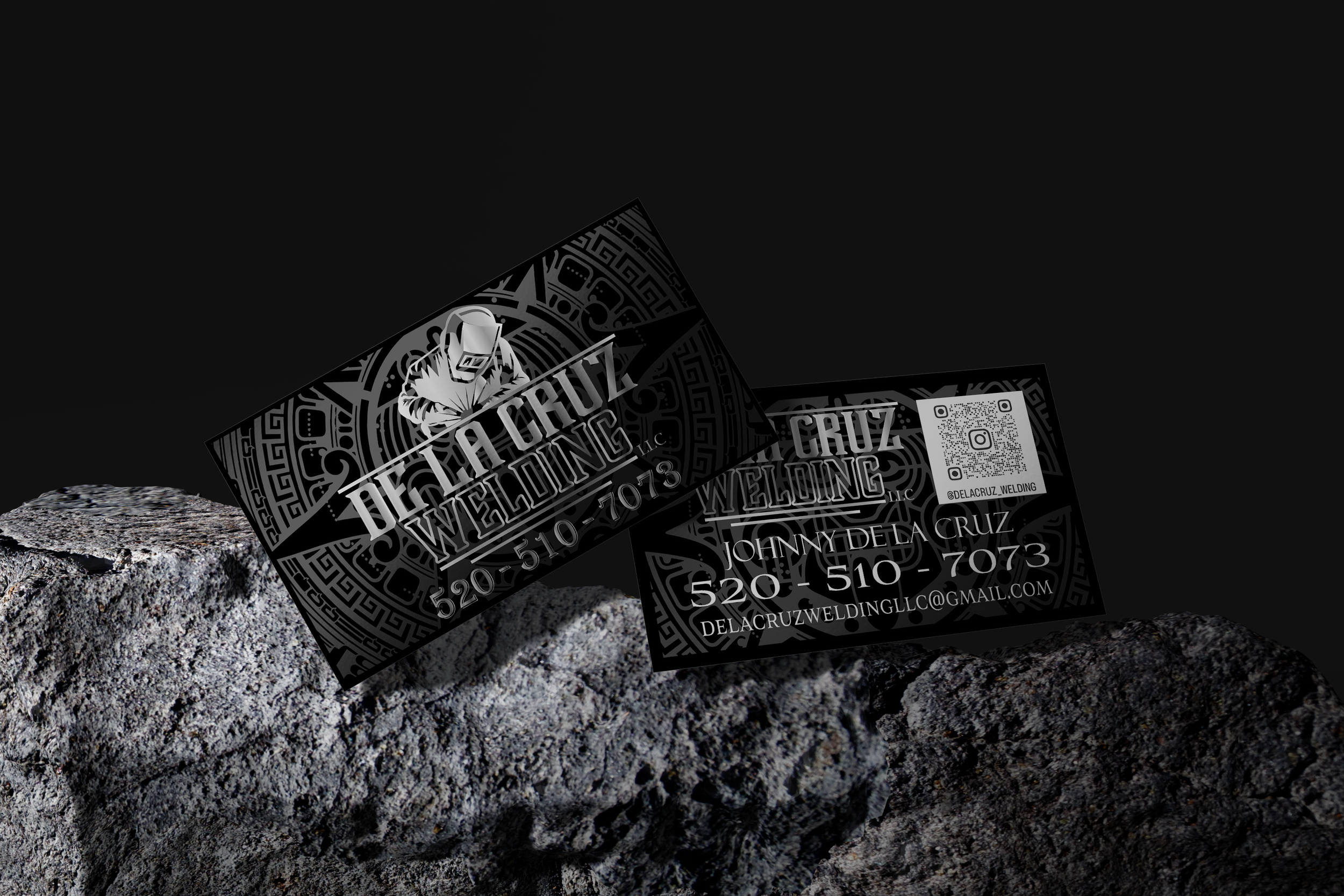 Business cards for Delia Cruz Welding, Inc. on rough rock surface against black background, featuring a logo of a welder, QR code, contact details, and social media handle.