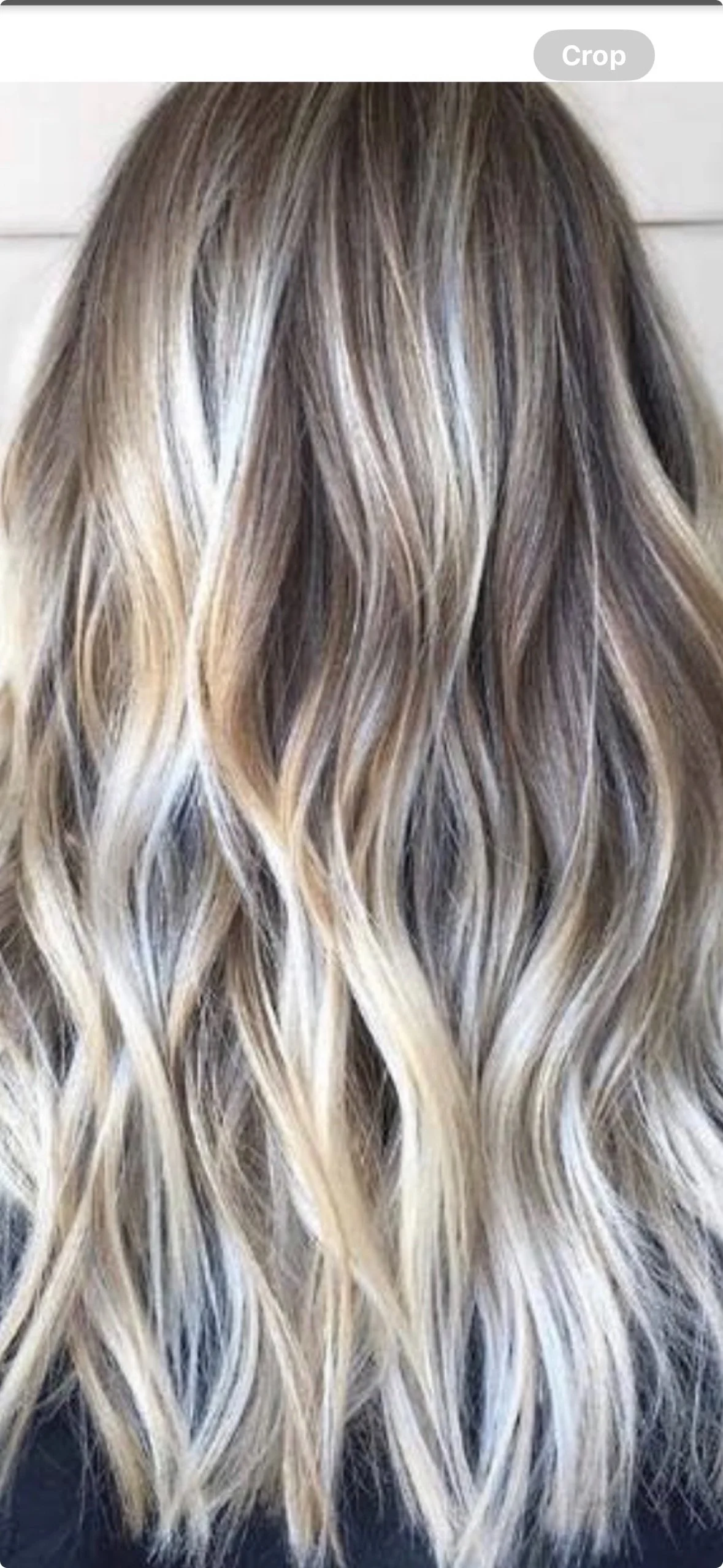 Back view of long, wavy, blonde hair with darker roots.