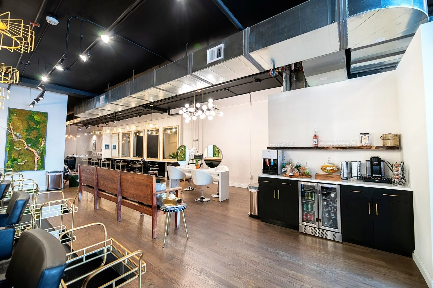 Interior of a modern lounge or cafe with black ceiling and wood flooring, featuring seating areas, a bar, and decorative lighting.