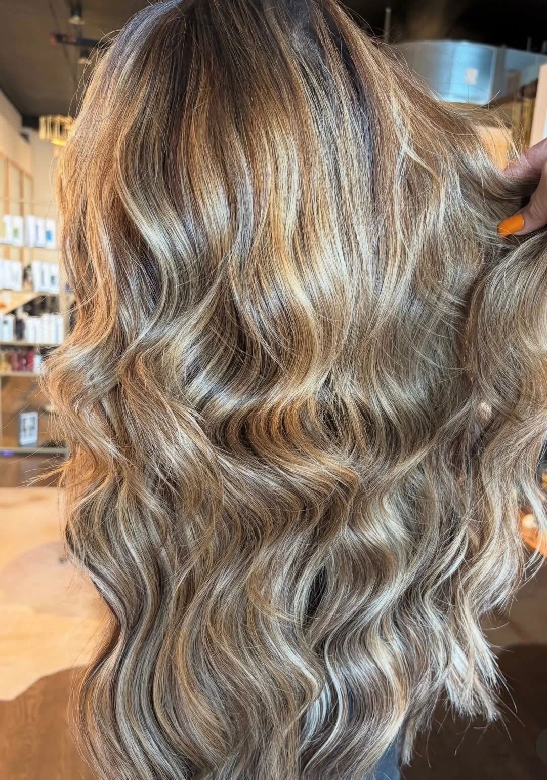 Close-up of wavy, blonde hair with highlights in a salon setting.