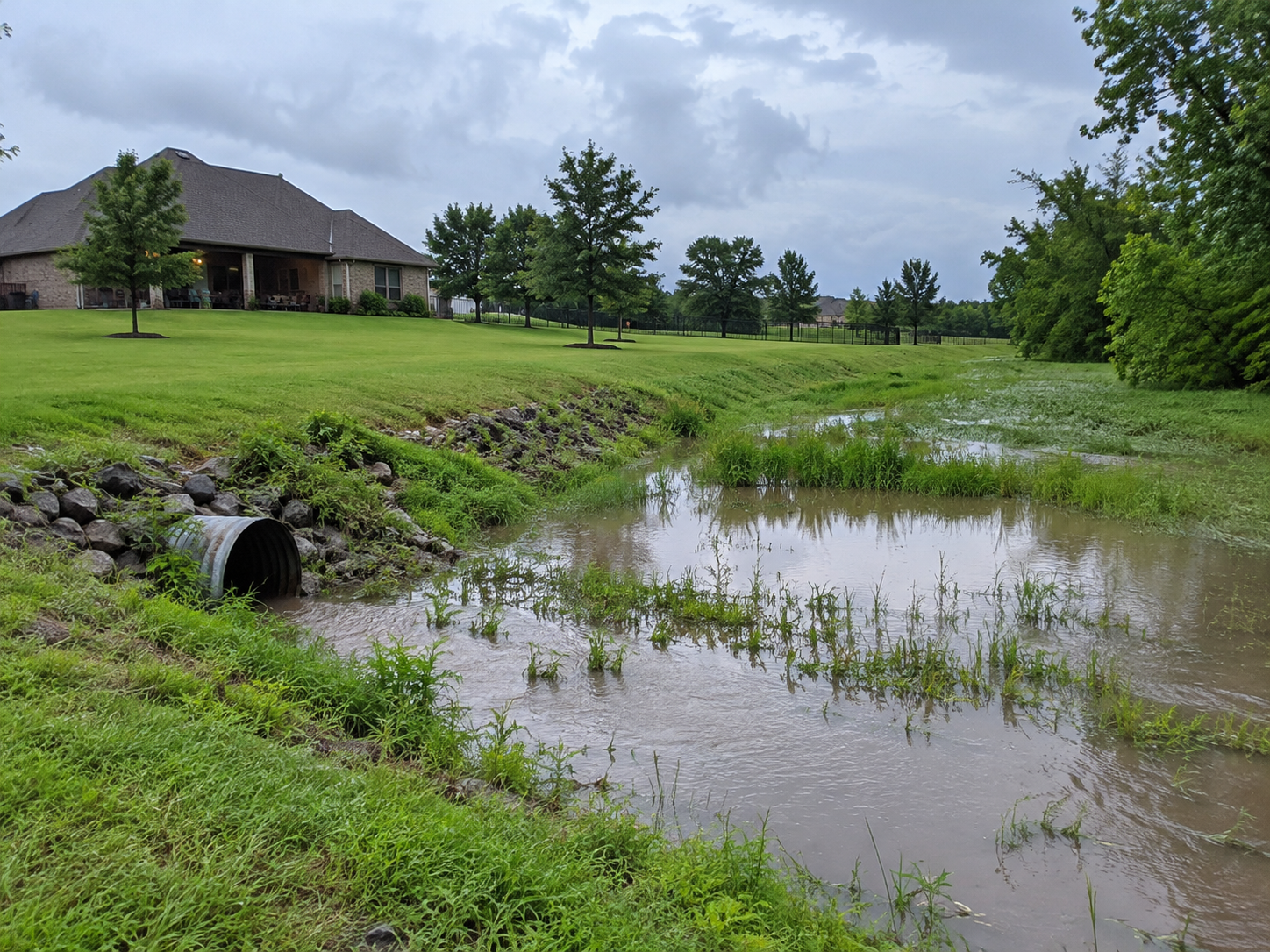 Stormwater runoff flowing through a culvert on rural Oklahoma acreage after heavy rain