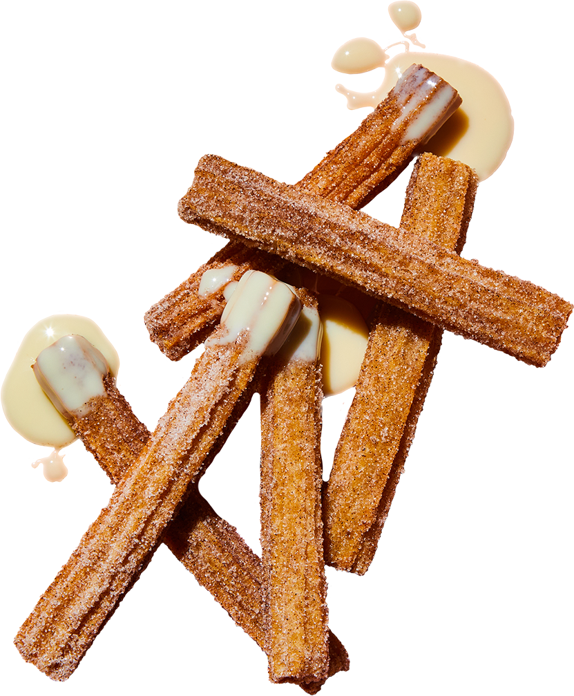 Close-up of churros topped with white chocolate and surrounded by white chocolate sauce.