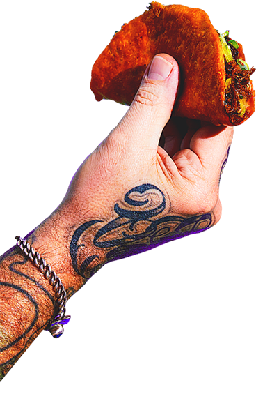 A hand holding a taco with visible toppings including meat and lettuce.