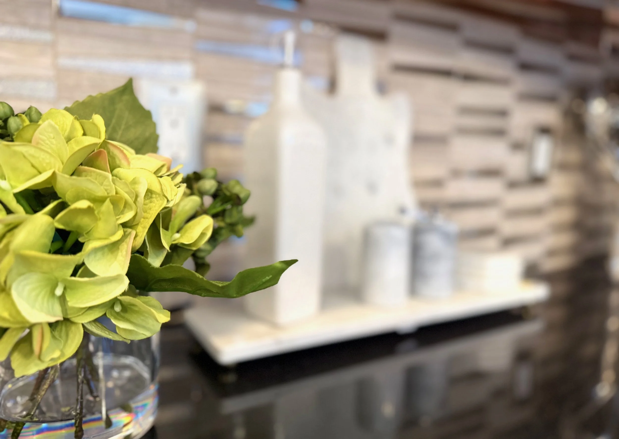 green flowers in glass vase, marble cutting board, marble salt and pepper shakers, marble coasters, tan and mirrored backsplash
