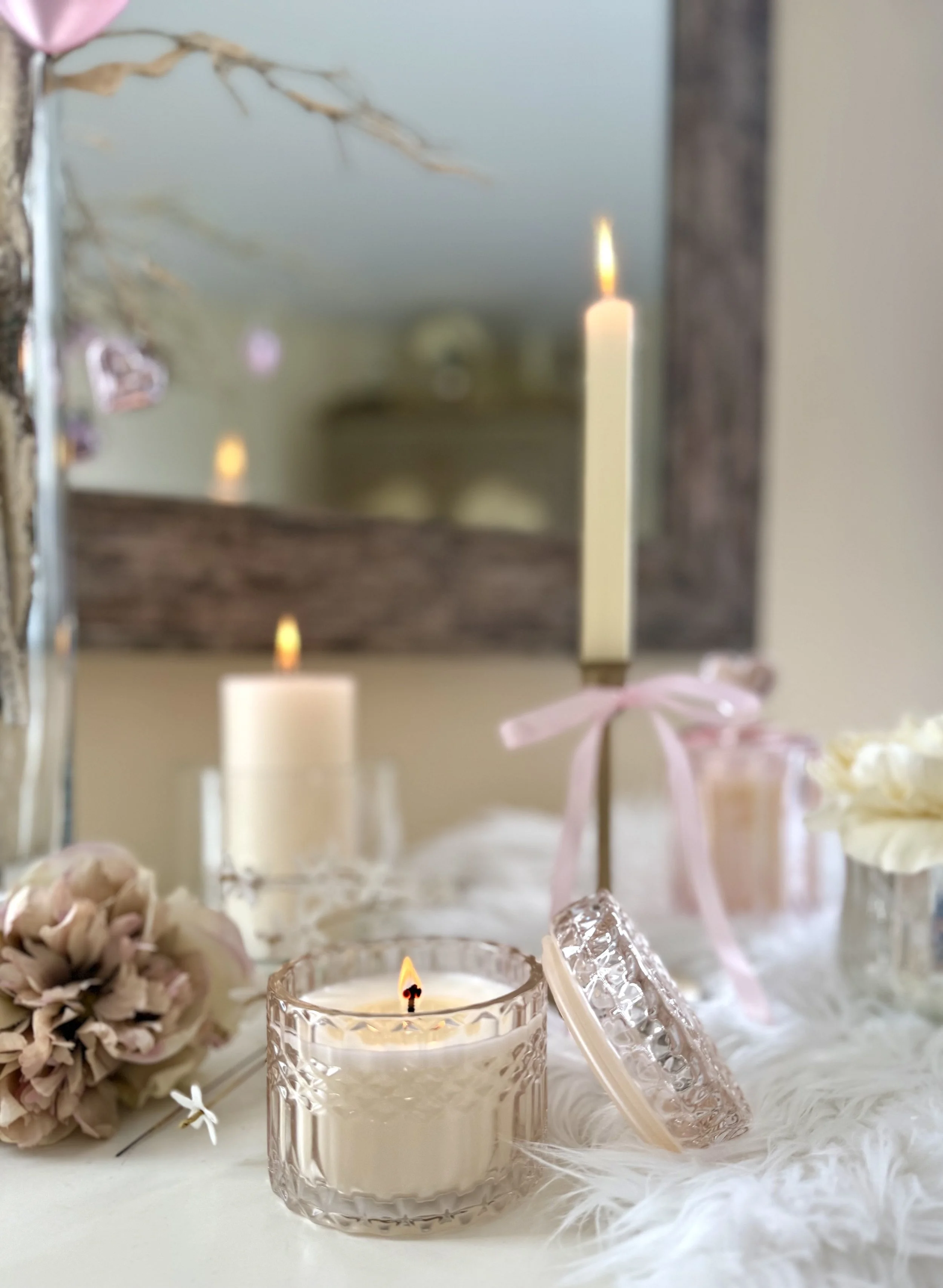 Valentine's Day tabletop decor with pink heart ornaments, candles, soft florals, and romantic accents including a distressed wooden mirror which adds contrast to the softness of the pink and white.
