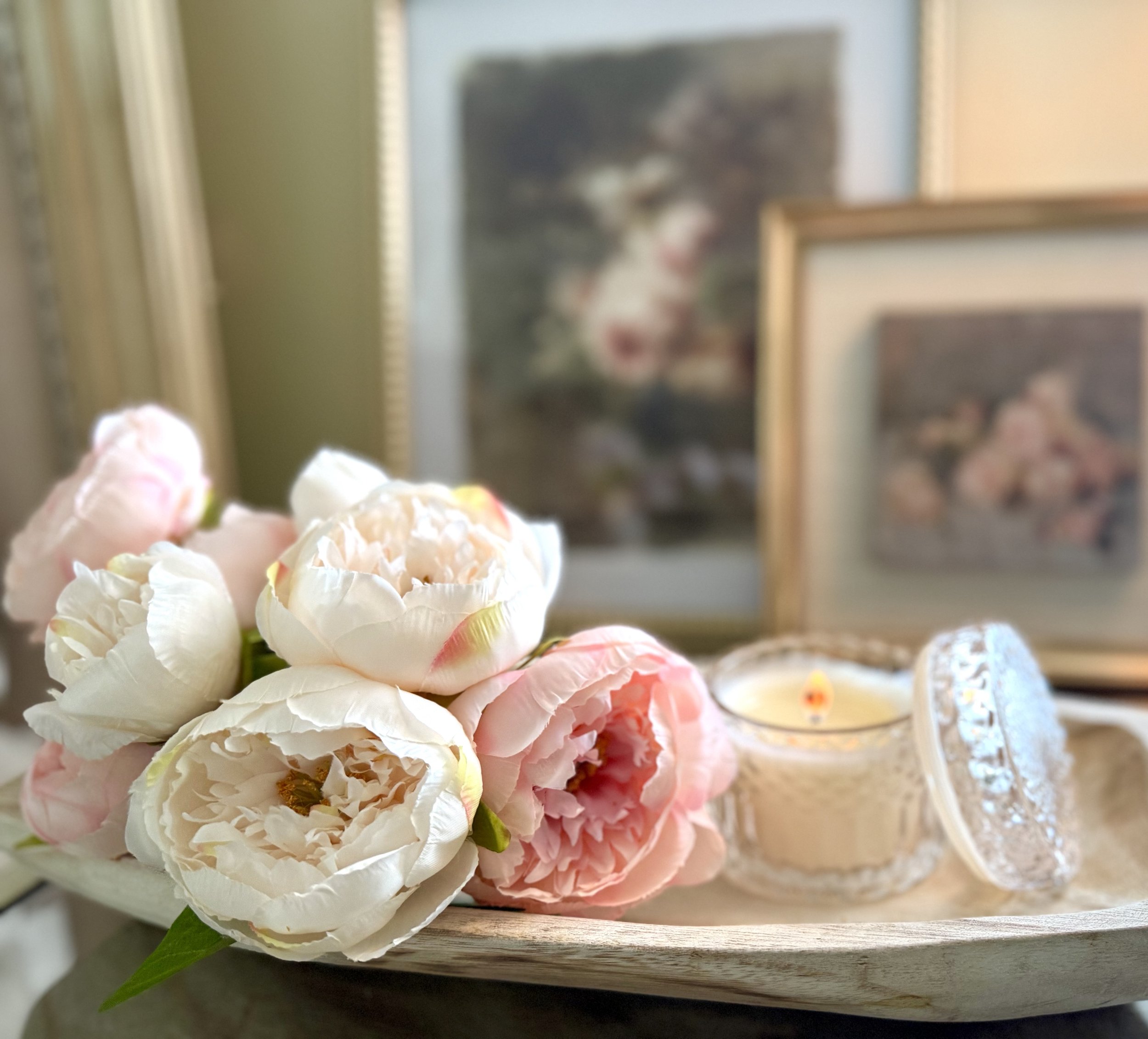 Valentine's day decor featuring soft pink peonies, candlelight in a wooden oval shaped bowl and layered pink art in gold frames