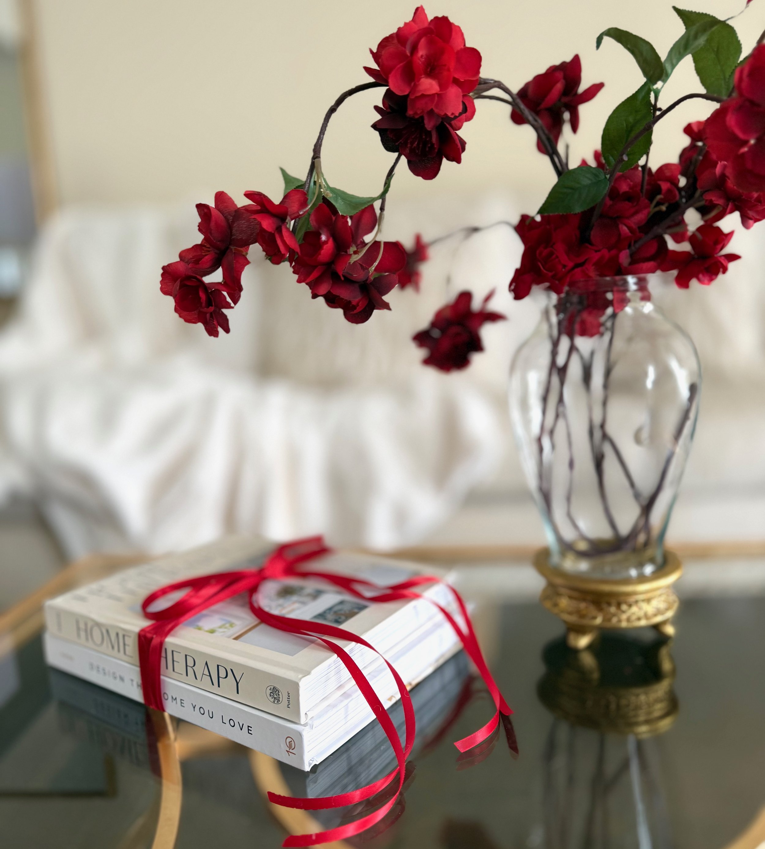 Red flowers, gold and glass vase, white books tied with a red ribbon