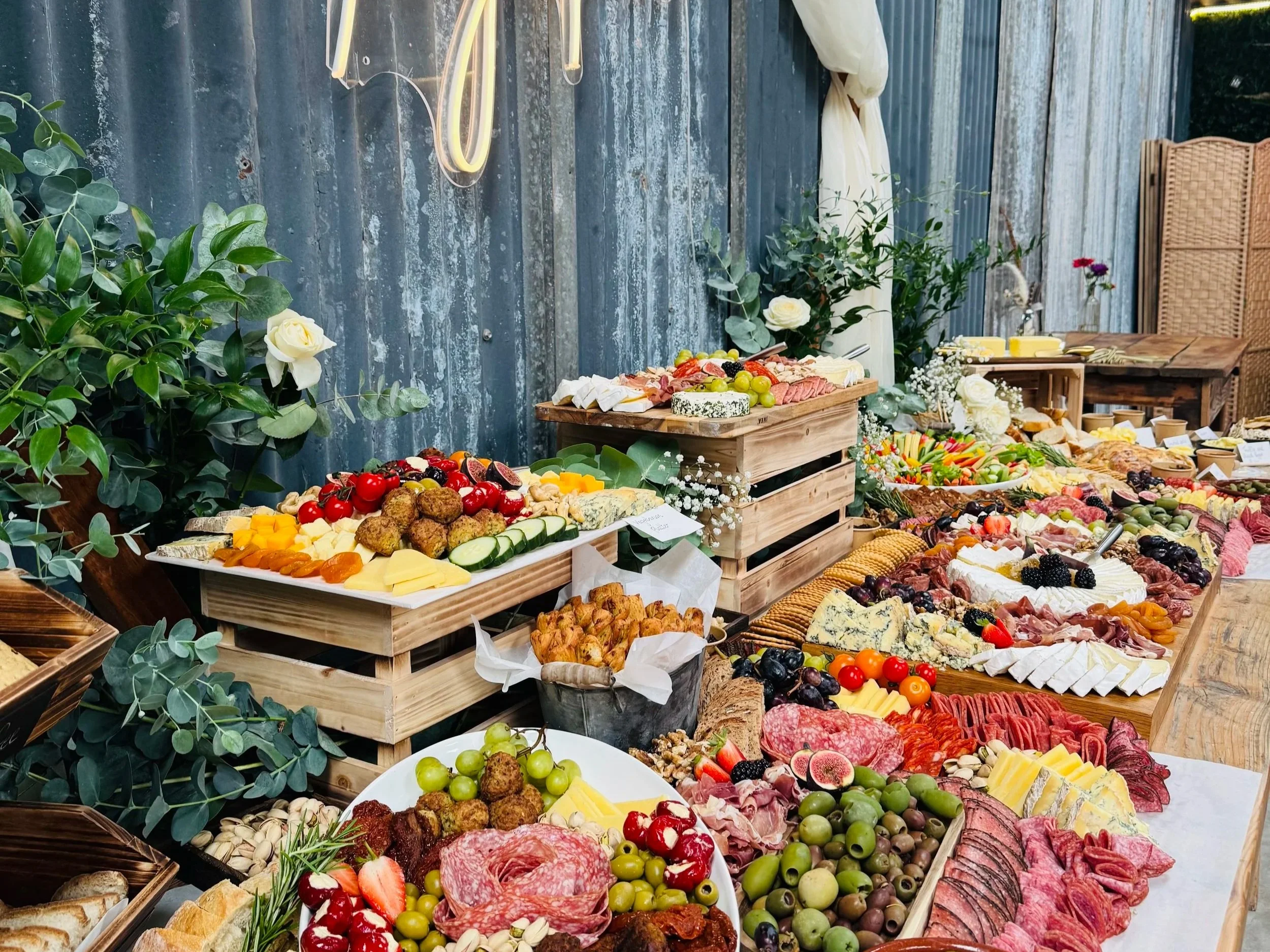 Rustic grazing table with artisan cheeses, cured meats, fresh fruits and flowers, styled for a spring baby shower.