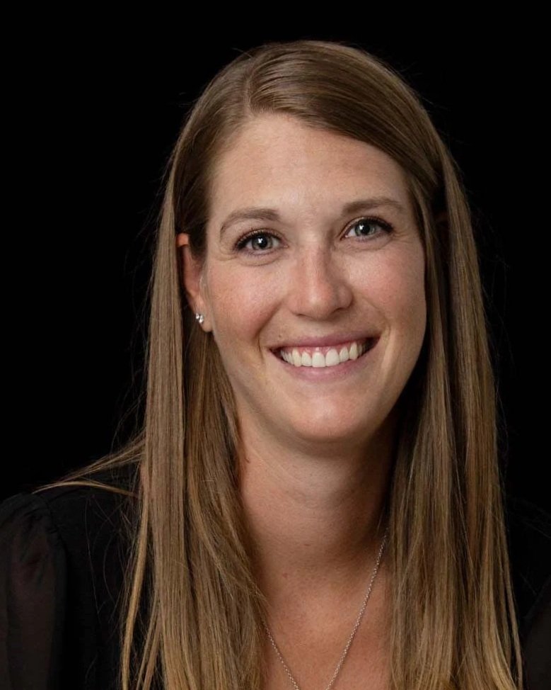 A brown haired woman smiling in front of a black background