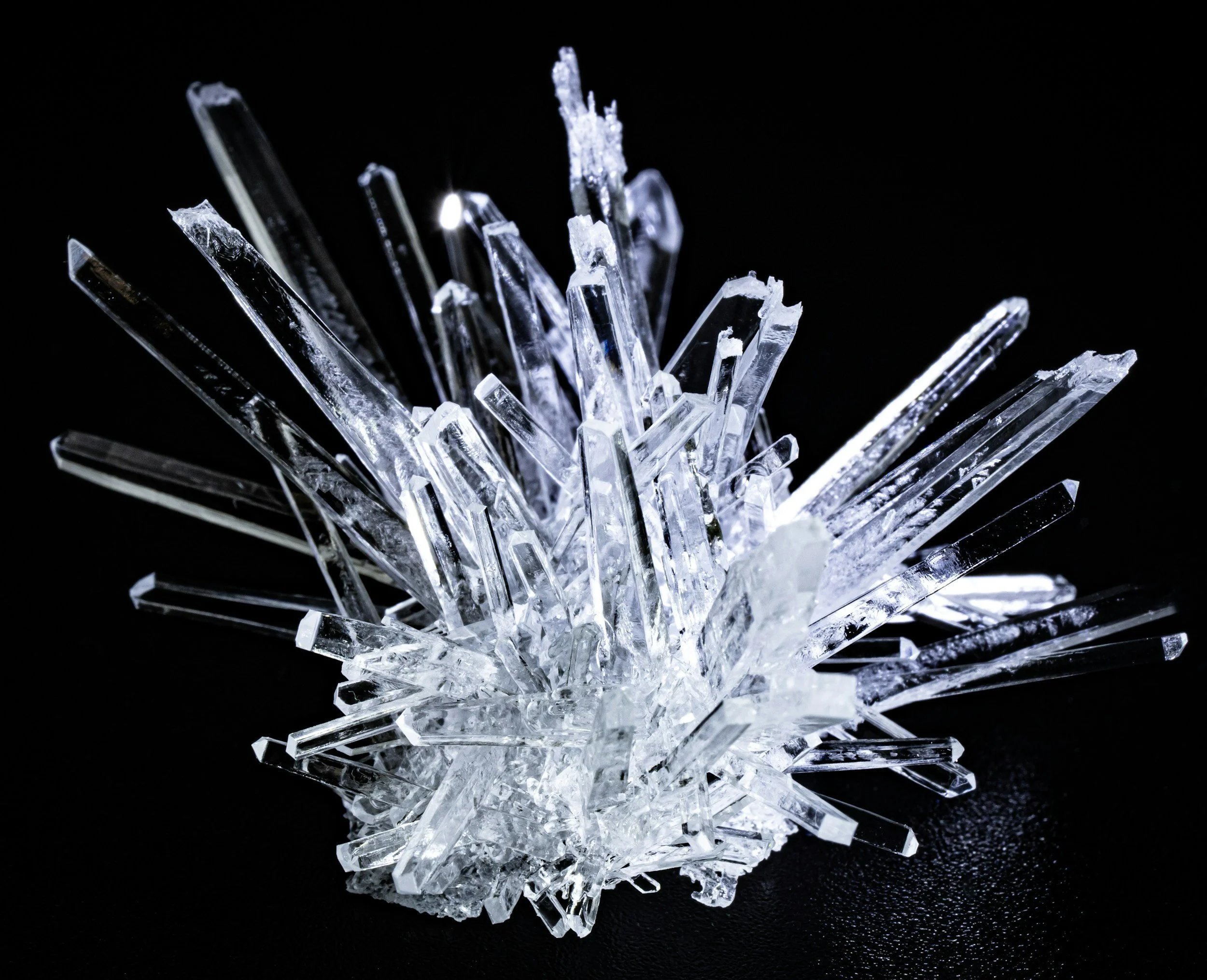 Close-up of a cluster of clear, sharp ice crystals against a black background.