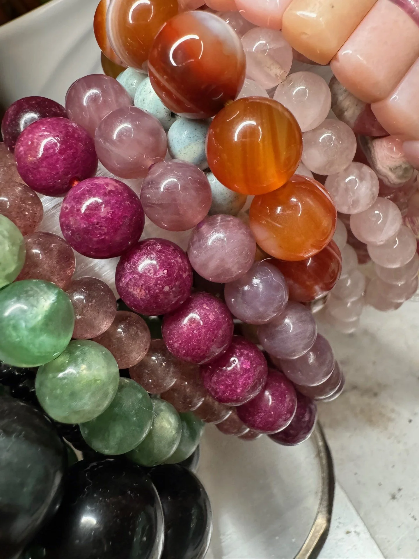 Close-up of various polished semi-precious gemstone spheres in colors including green, pink, purple, orange, and clear, arranged in a display.