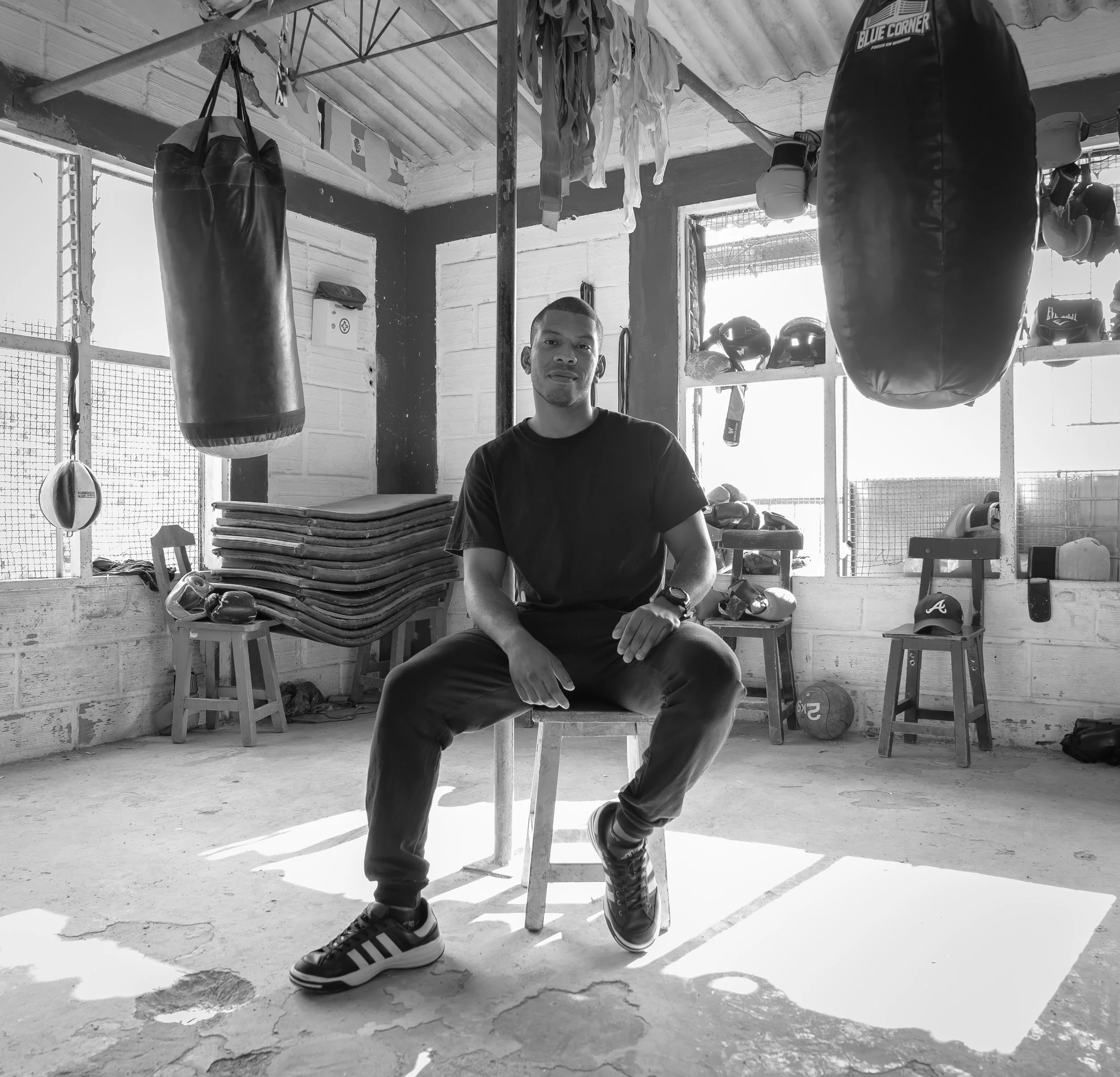 Black and white portrait of a man on a stool in a boxing gym