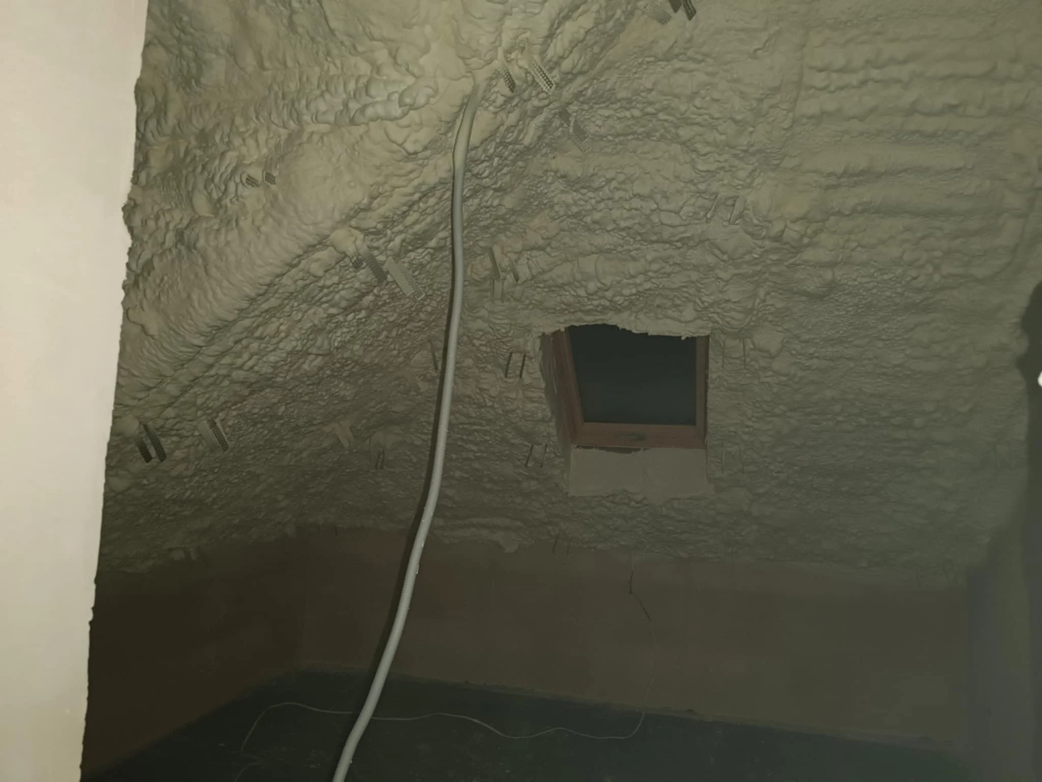 Ceiling with spray foam insulation, electrical wiring and metal fasteners, window in the attic or ceiling space.