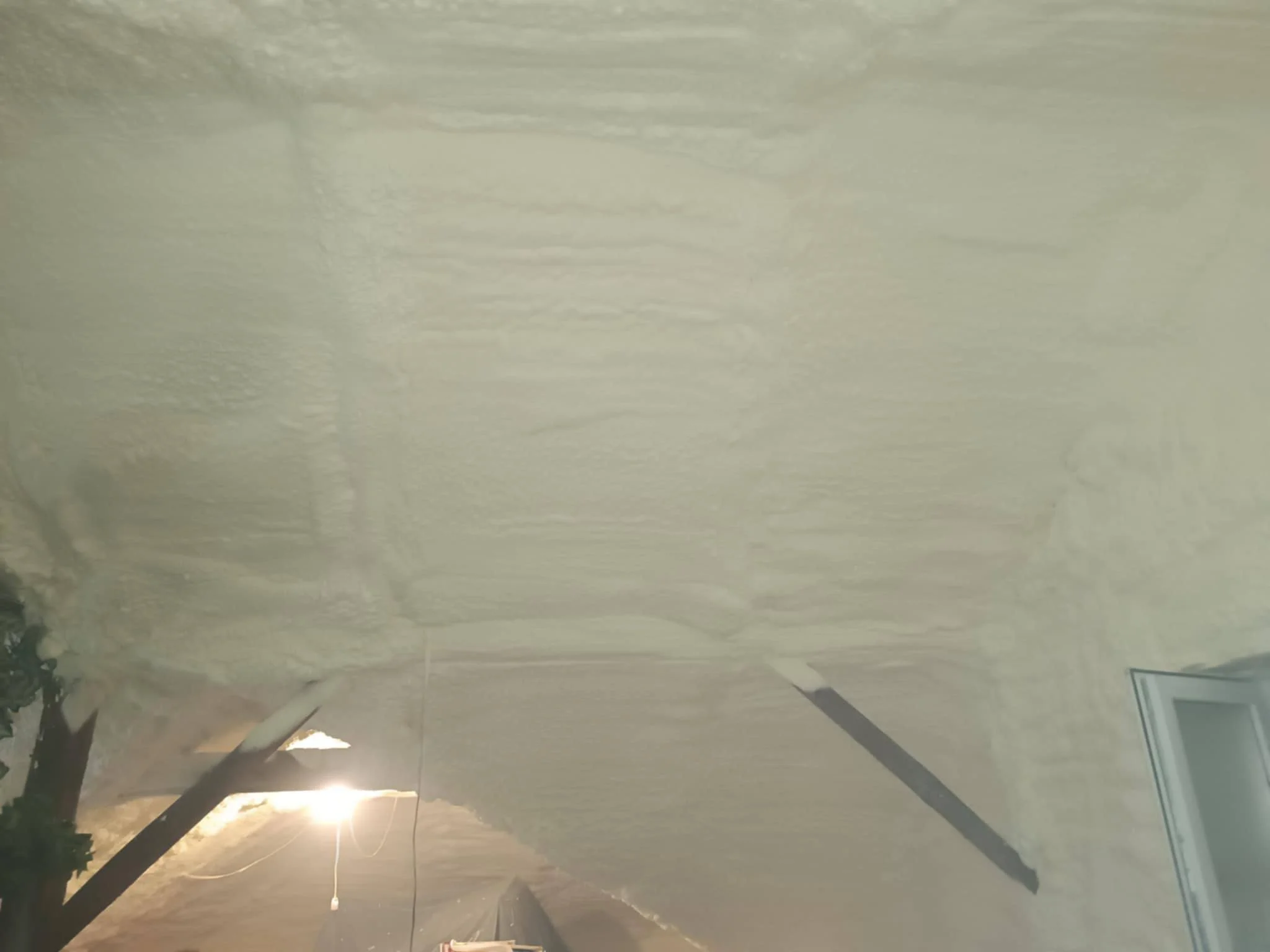 Indoor ceiling with patchy insulation or spray foam insulation, a ceiling vent, and interior lighting.