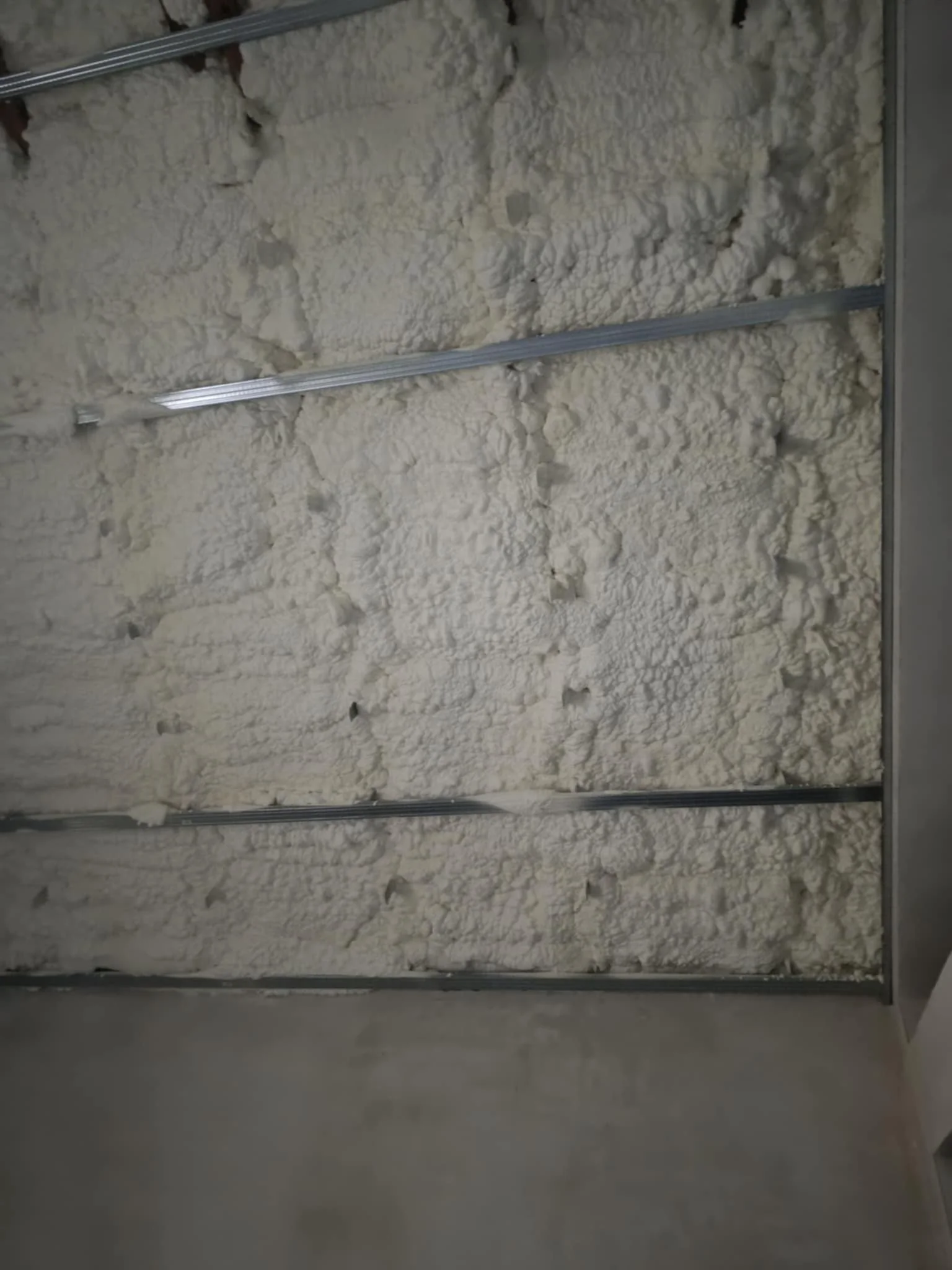 Image showing a wall with spray foam insulation installed between metal framing studs.