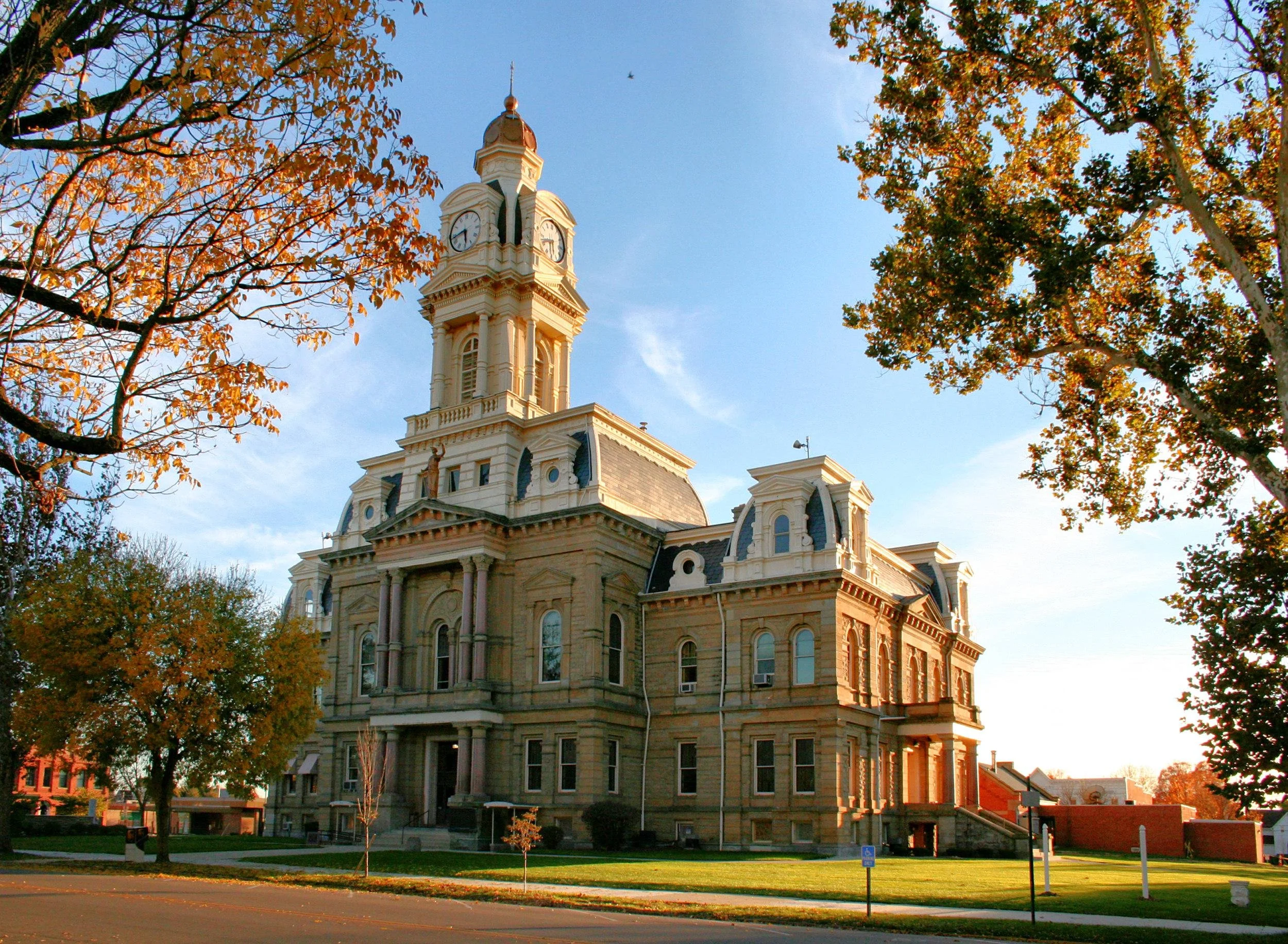 A historic courthouse building with a clock tower, surrounded by trees with autumn leaves.
