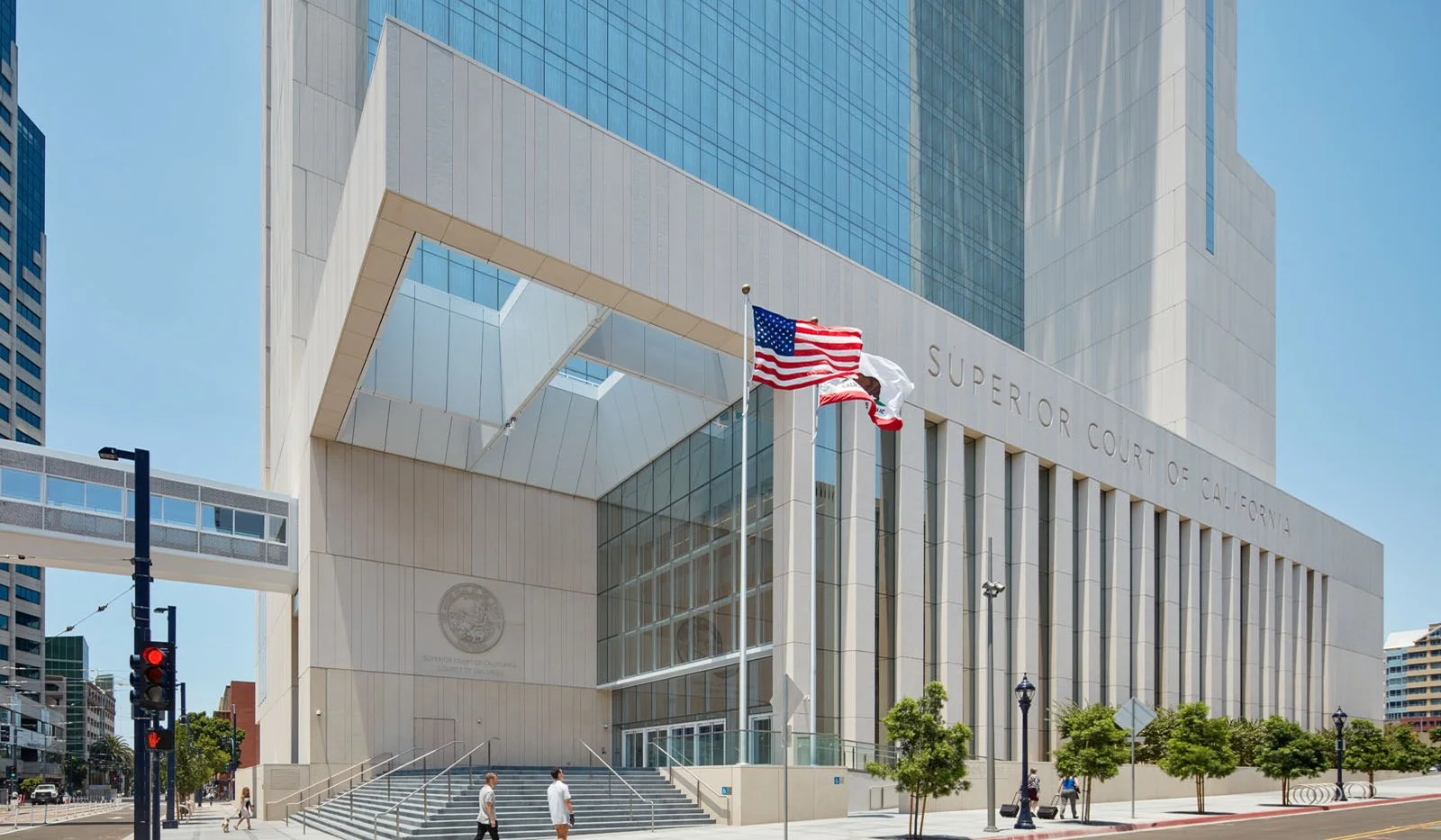 Modern courthouse building with a large overhang, glass facade, and the words 'Superior Court of California' on the front, with American and California flags flying outside.
