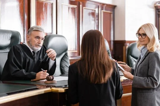 A courtroom scene with a judge, a lawyer, and a woman in a legal setting.