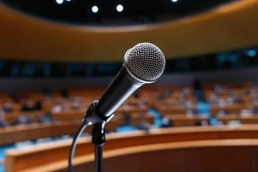 A microphone on a stand in front of an auditorium or conference hall with empty seats.