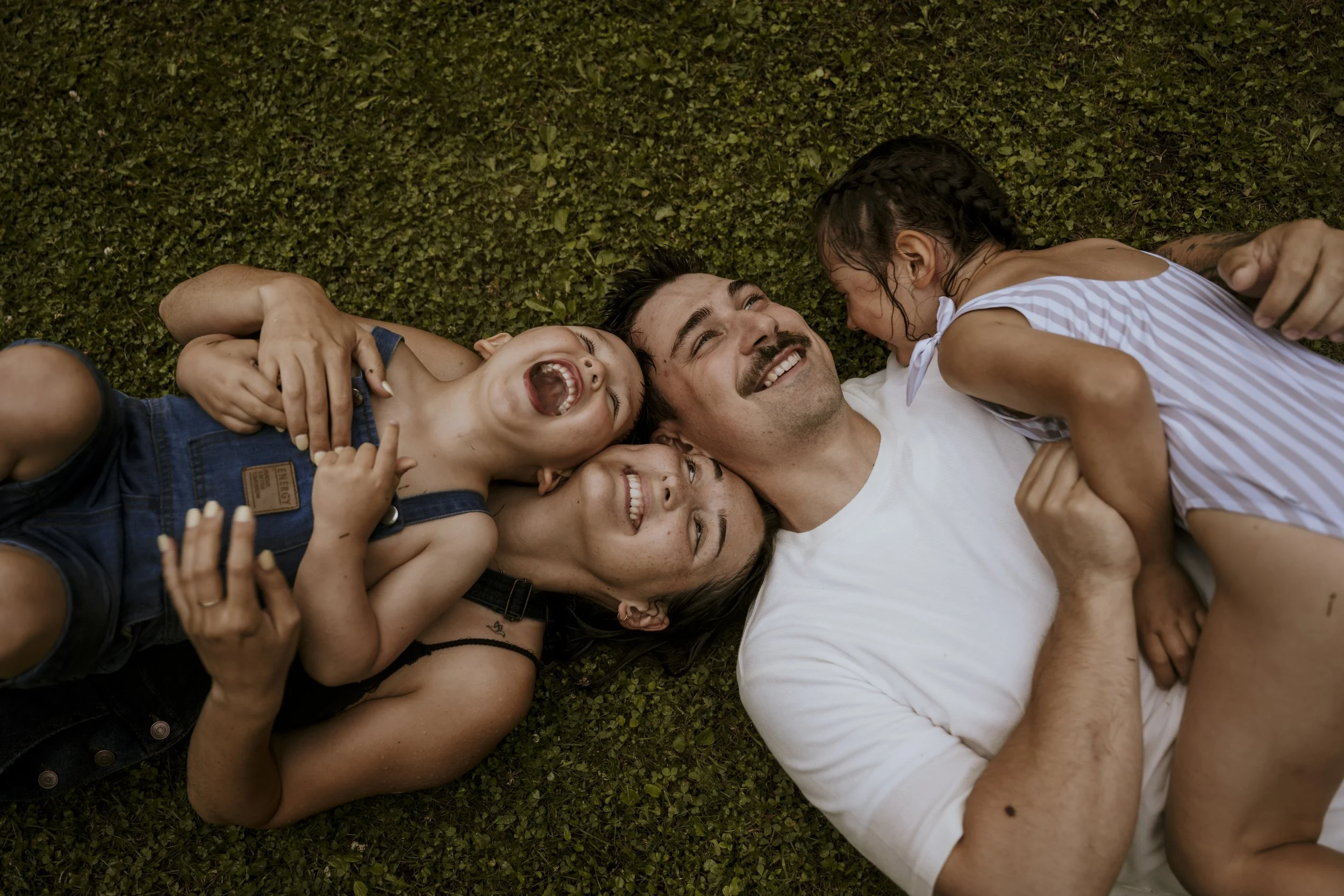 Une famille qui s'amuse à se rouler dans le gazon mouillé après une guerre d'eau un beau soir d'été