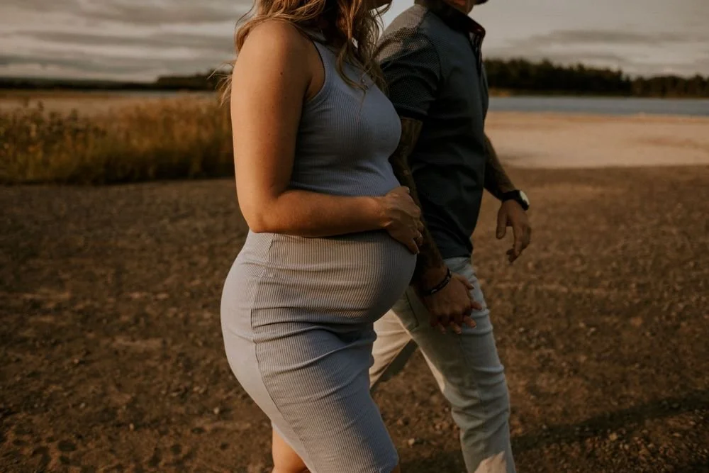 Femme enceinte tenant la main de son conjoint au coucher du soleil en été