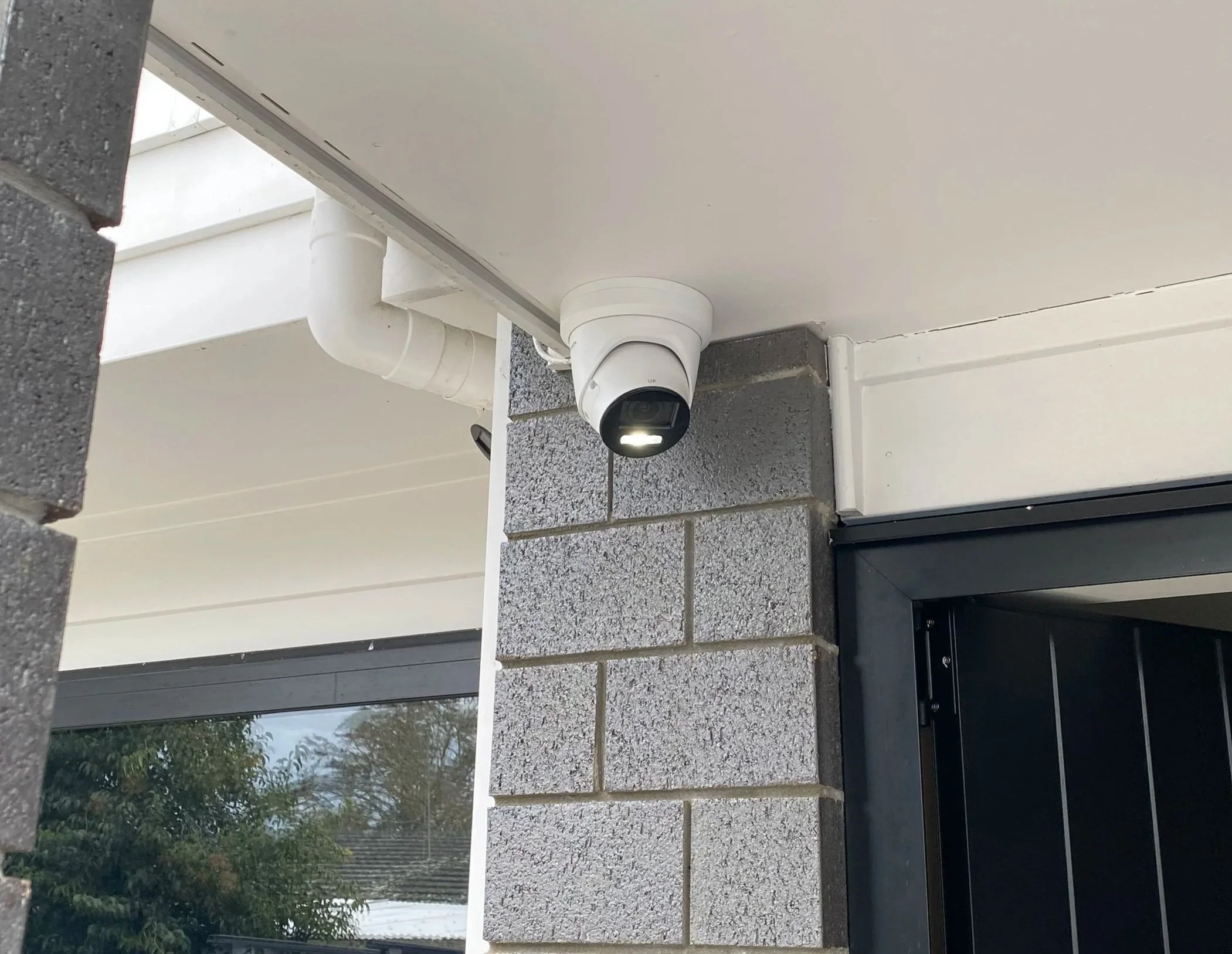 Close-up of a professionally mounted dome security camera on the corner of a residential building