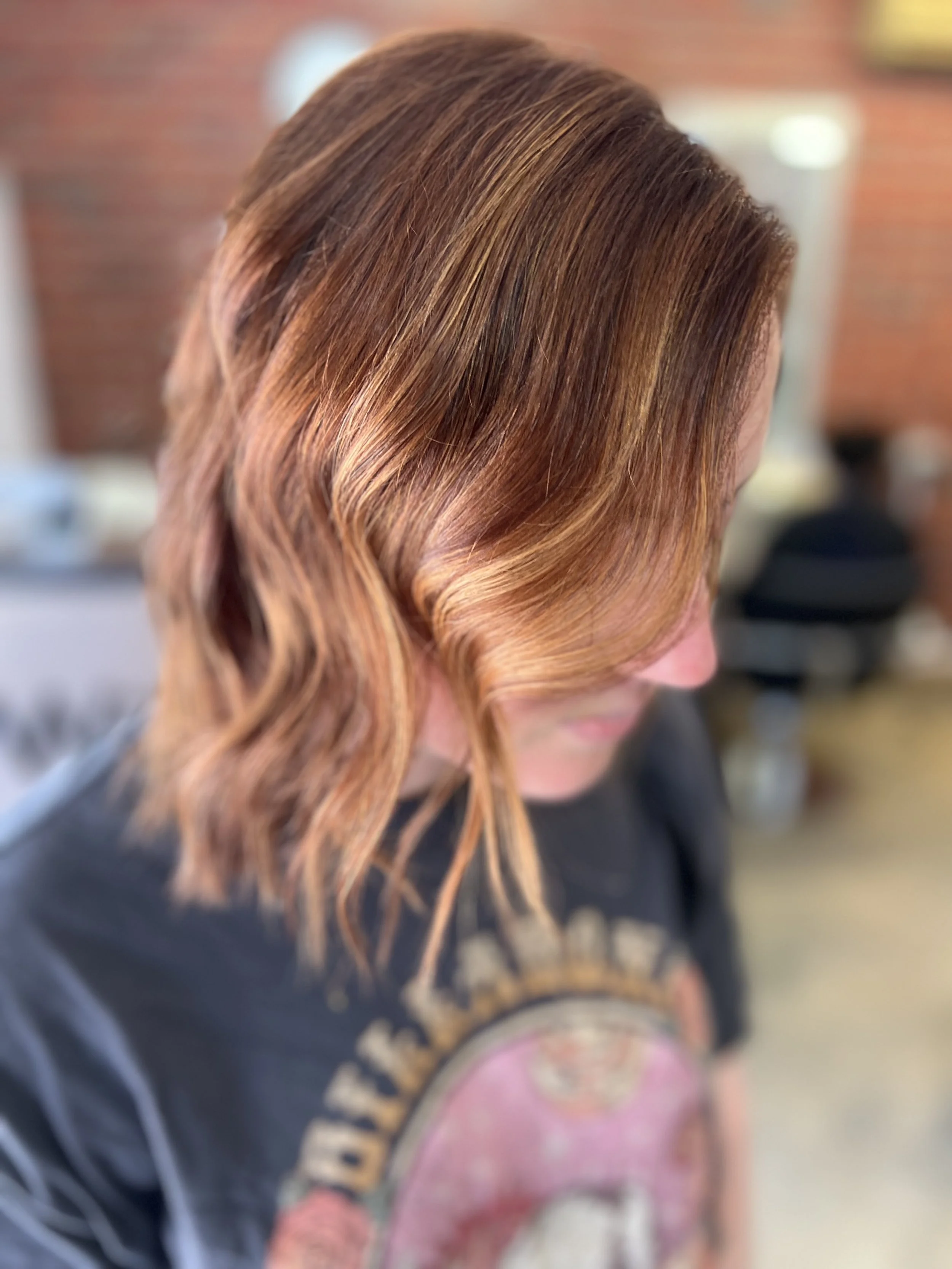 Close-up of a woman with shoulder-length wavy hair that is a mix of light brown and blonde highlights.