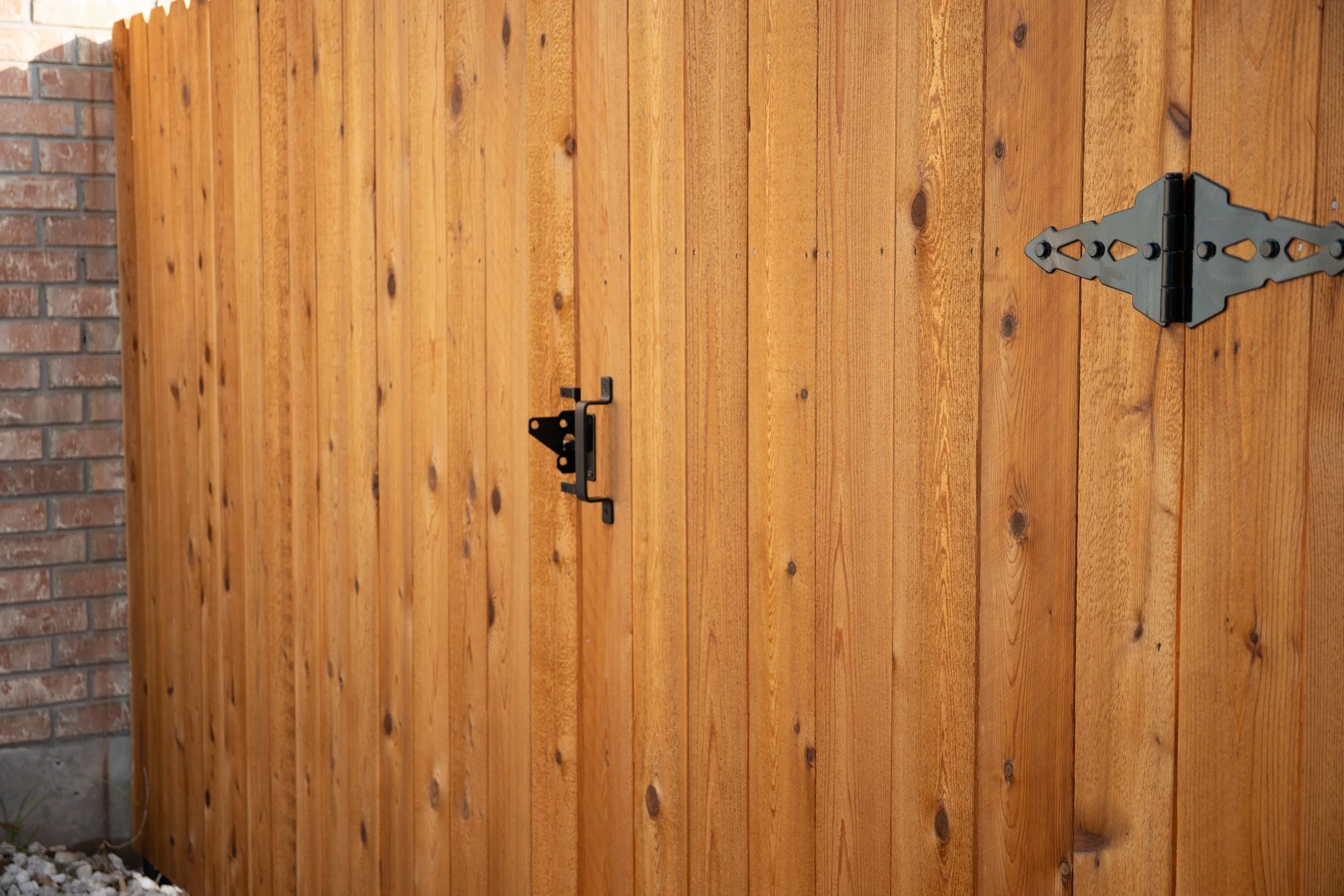 A wooden fence with a latch and a hinge.