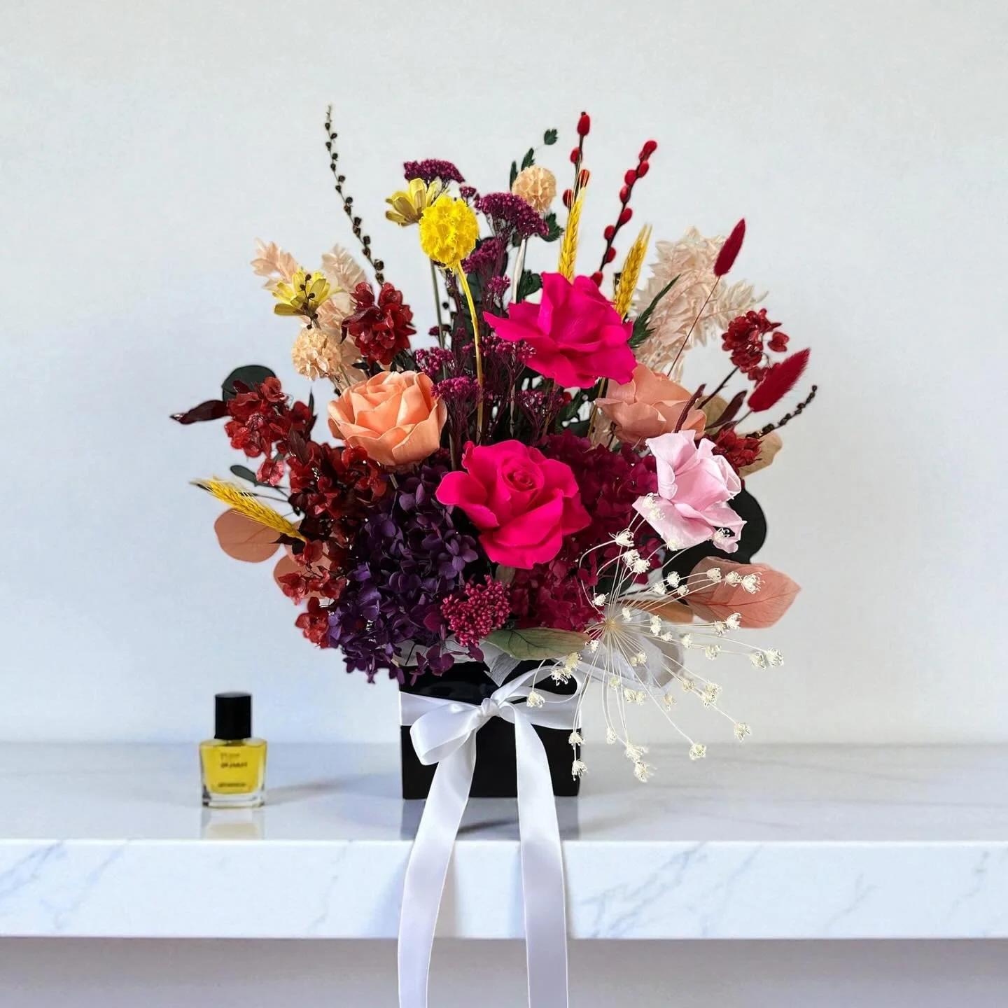 Bursting with bold colour and texture &mdash; our Little Vivienne arrangement is made for making an entrance.

Standing around 70 cm tall, this luxe dried floral design features layers of fuchsia, coral and deep plum, hand-crafted in our signature gi