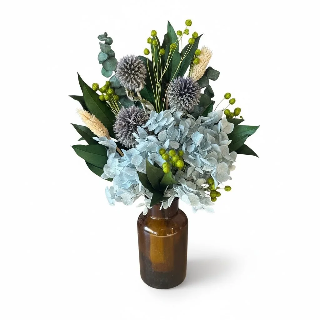 Little Holly 🌿

Soft blue hydrangea tones, textured thistle, fresh green accents and layered foliage come together in this petite but striking arrangement. Styled in an amber glass vase, she&rsquo;s earthy, modern and effortlessly beautiful, the per