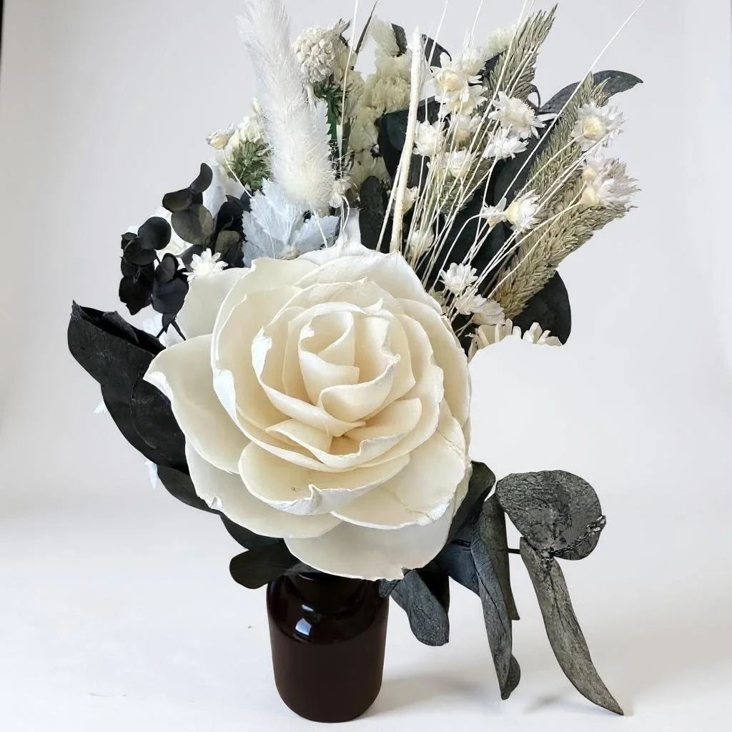 Elegant dried flower arrangement with white rose, billy buttons, bunny tails, statice and greenery in an amber vase