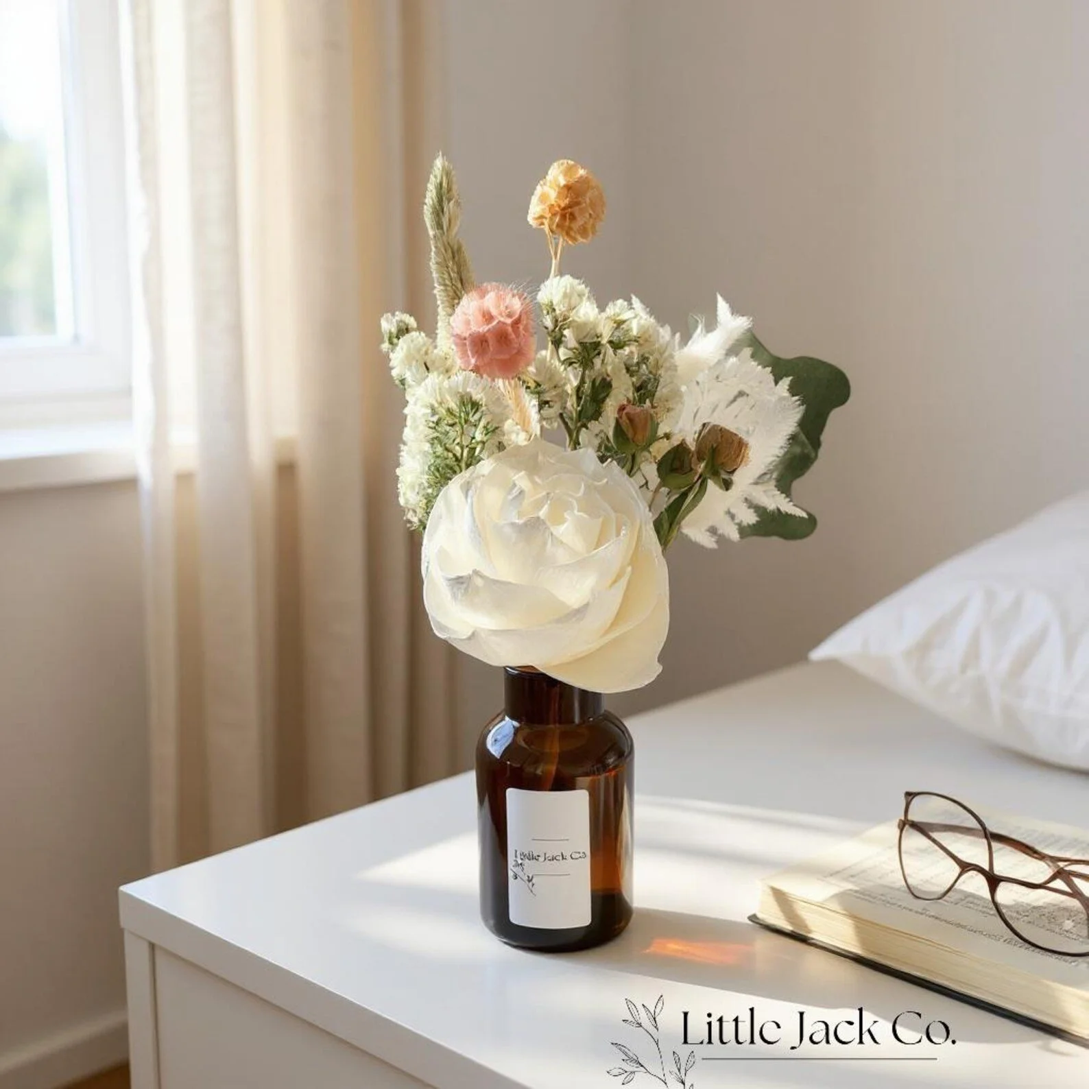 Elegant dried flower arrangement with a white rose, scabiosa, statice, fern and greenery in an amber vase.