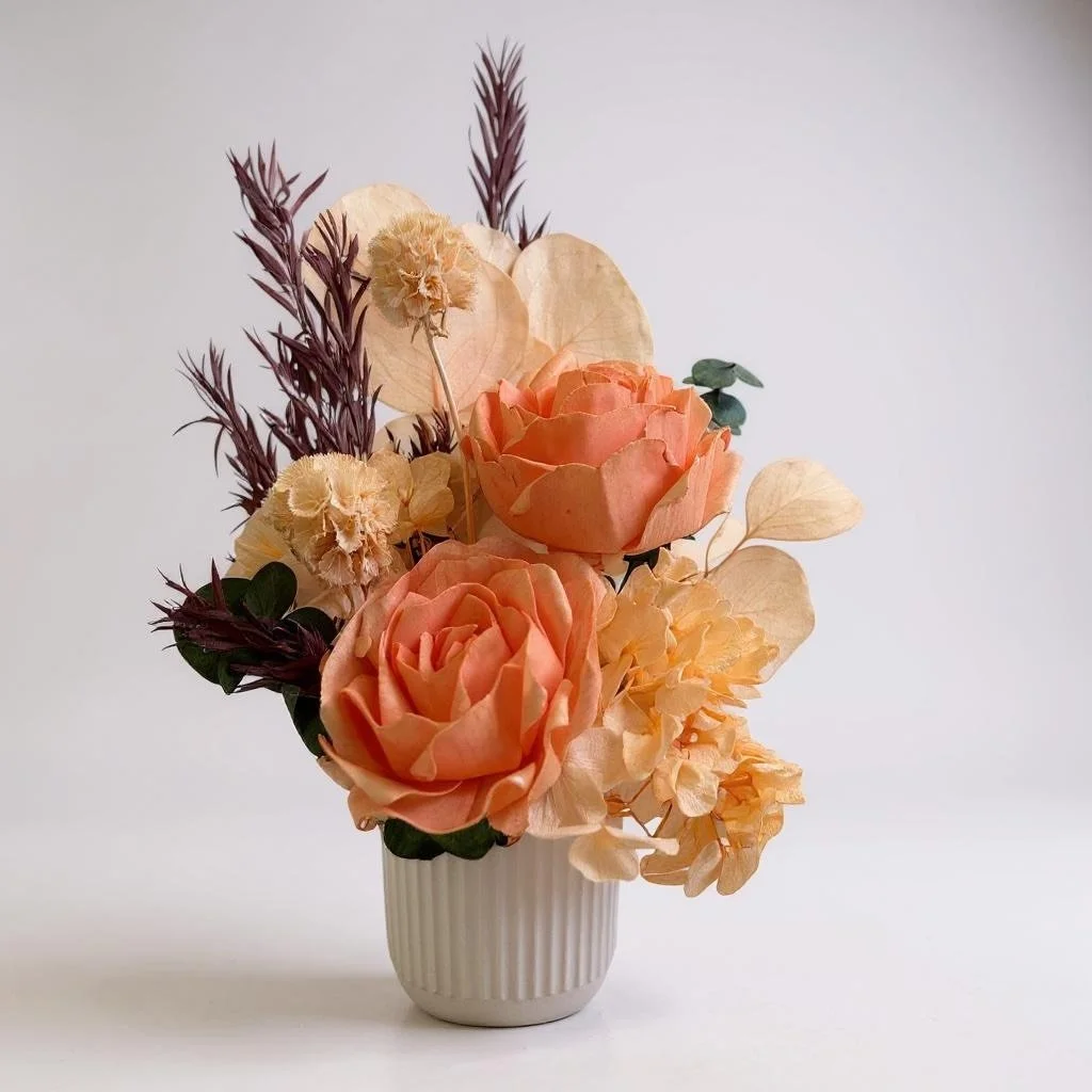 Dried flower arrangement with orange roses, apricot eucalyptus, apricot hydrangea in a ribbed ceramic vase