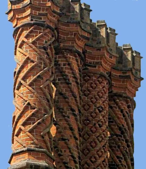 Close-up of a brick chimney with a twisted, spiraling design on a building against a clear blue sky.